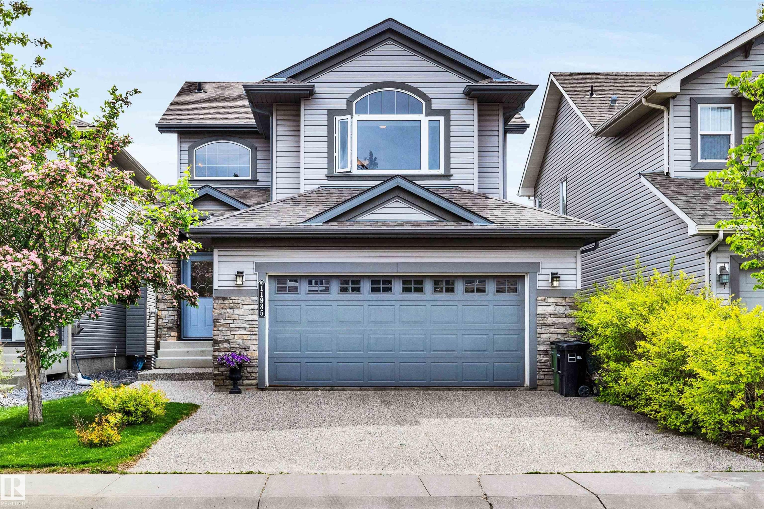 Two-story residence featuring light gray siding, stone accents, and a dual-car garage - 11935 21 Avenue, Edmonton, AB