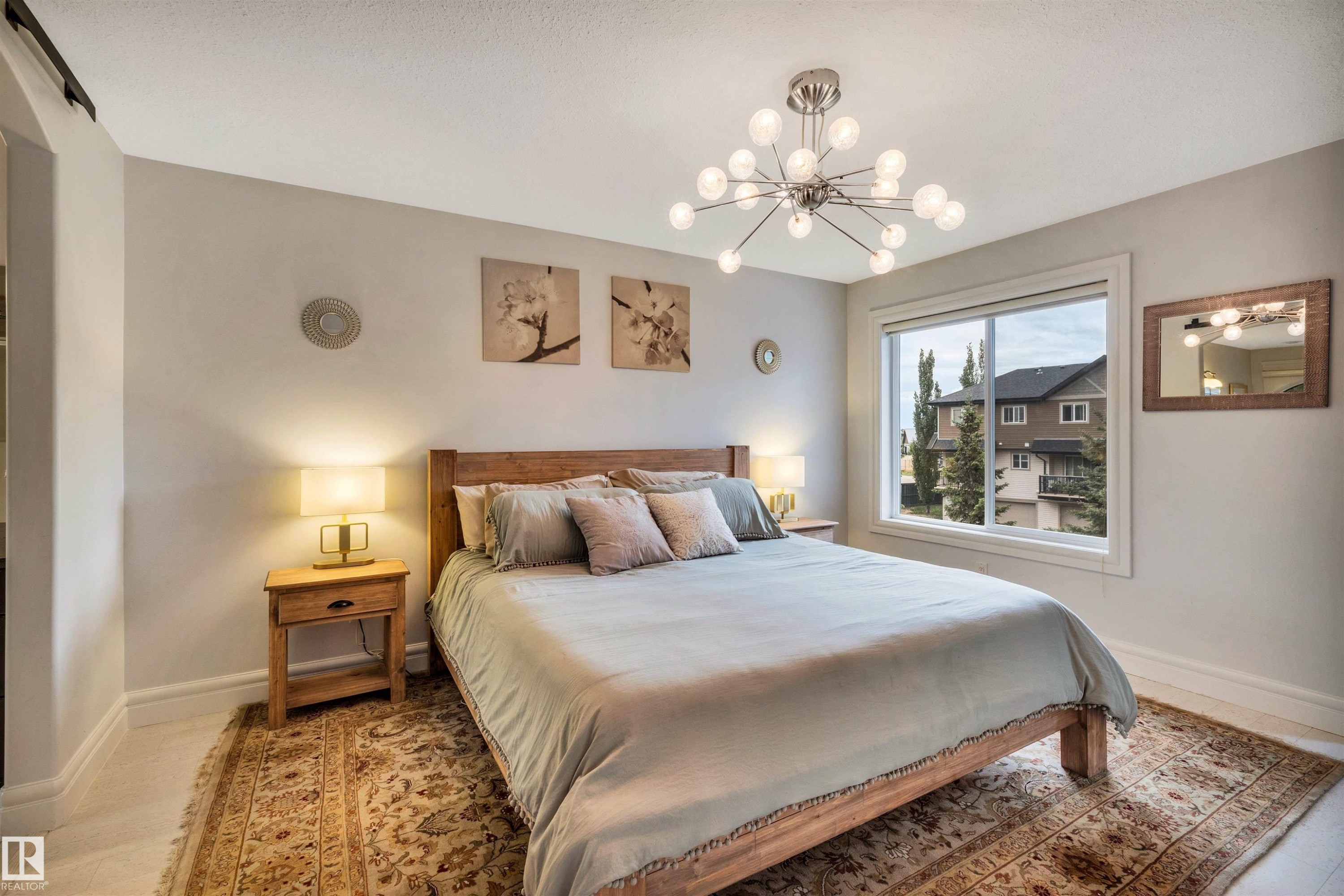 Bedroom featuring a modern sputnik chandelier, wood-finish flooring, and a large window - 11935 21 Avenue, Edmonton, AB