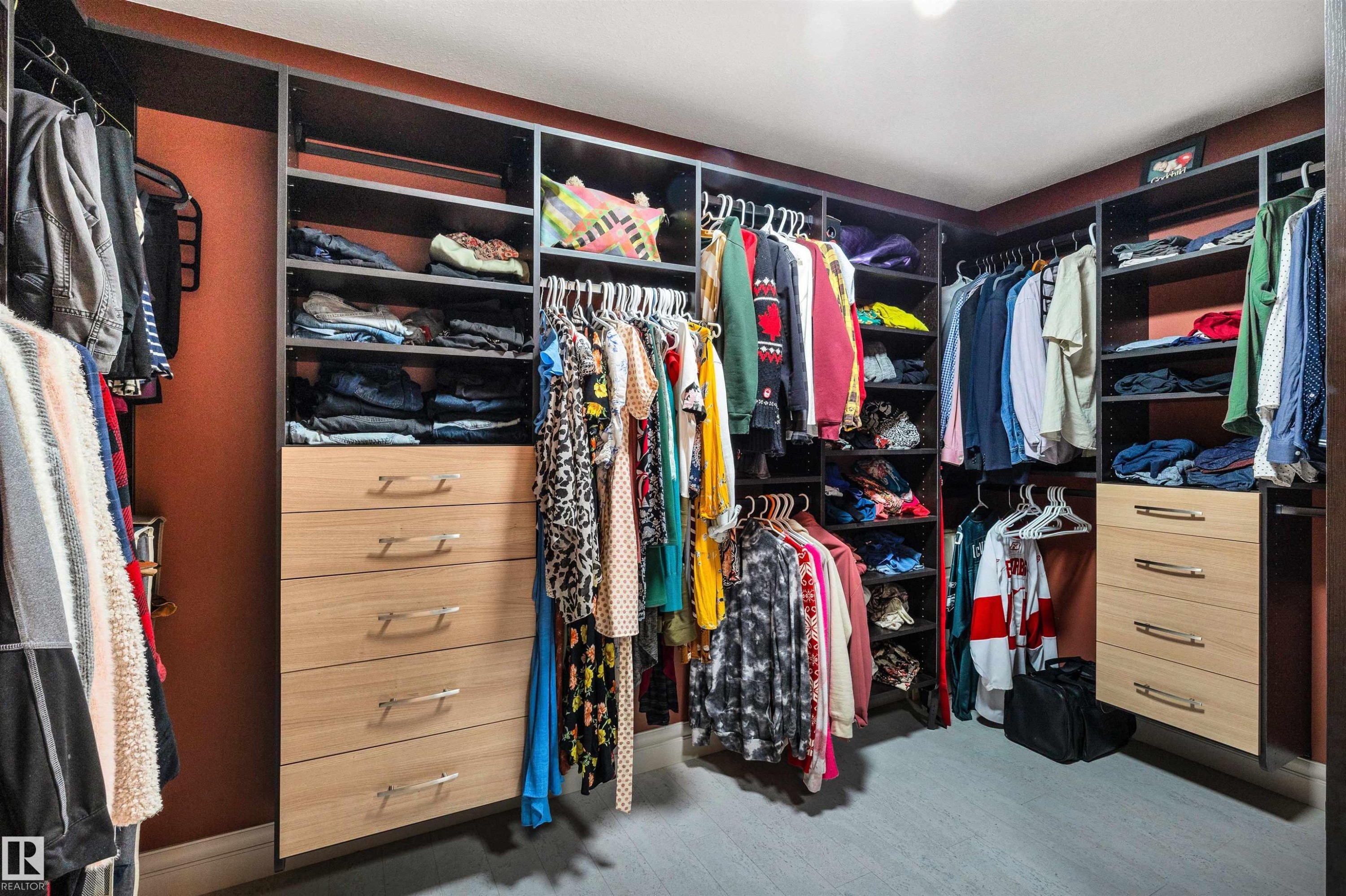 Custom closet system featuring dark wood-finish shelving, integrated hanging rods, and light wood-finish drawer units with horizontal pulls - 11935 21 Avenue, Edmonton, AB