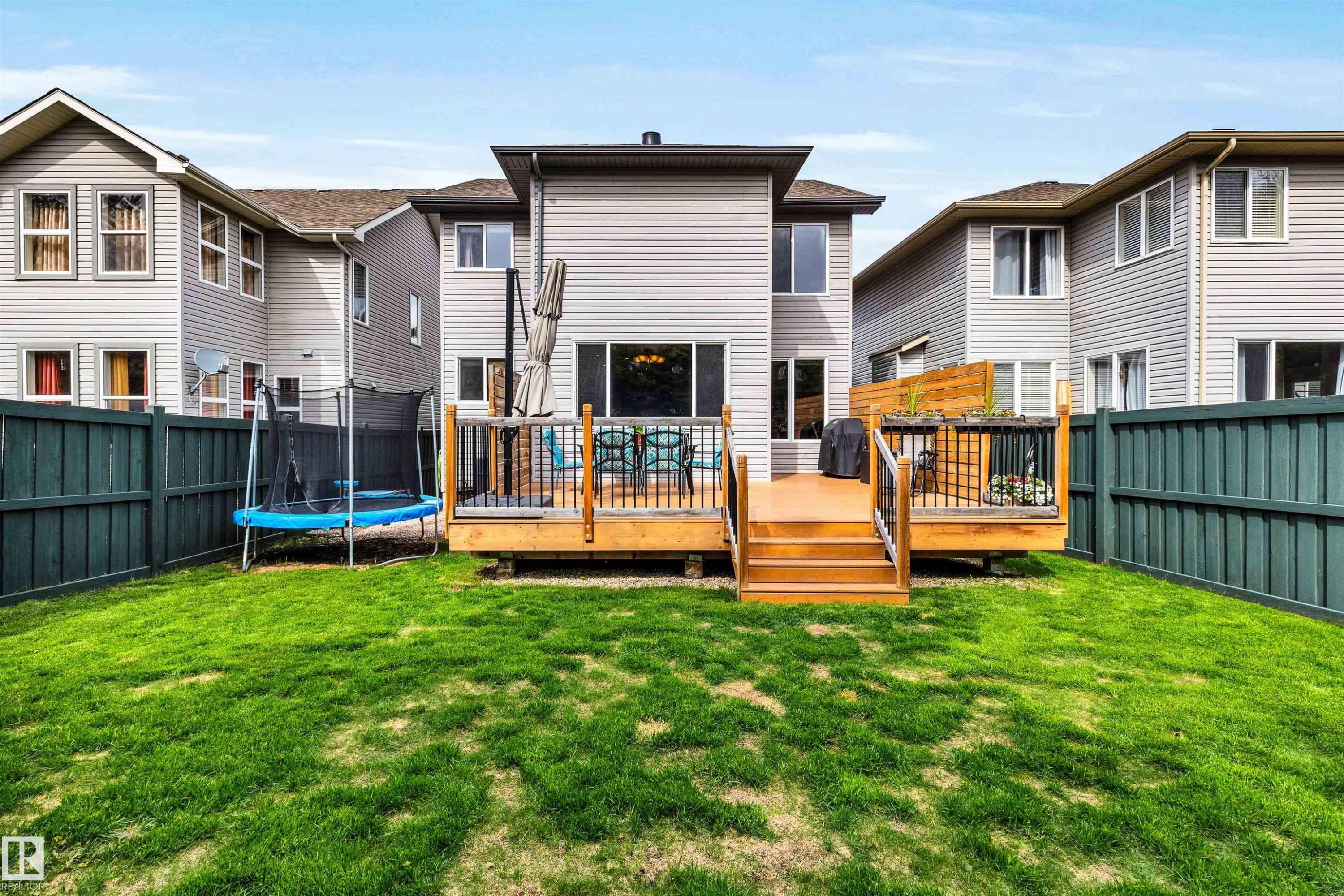 Expansive backyard featuring a manicured lawn, a multi-tiered wooden deck, and a privacy fence - 11935 21 Avenue, Edmonton, AB