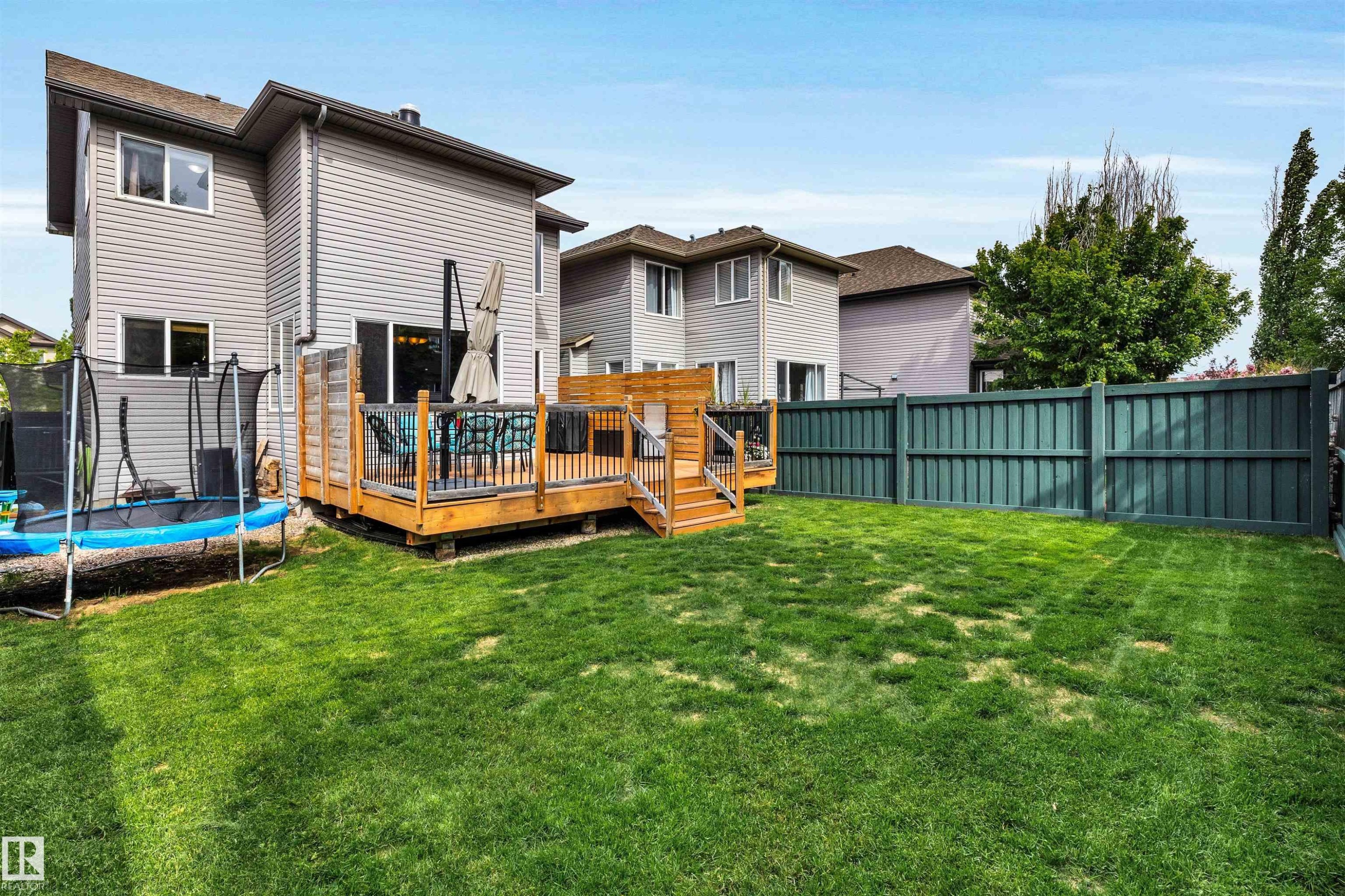 Spacious backyard featuring a multi-level wooden deck, a fully fenced perimeter, and a generous lawn area - 11935 21 Avenue, Edmonton, AB