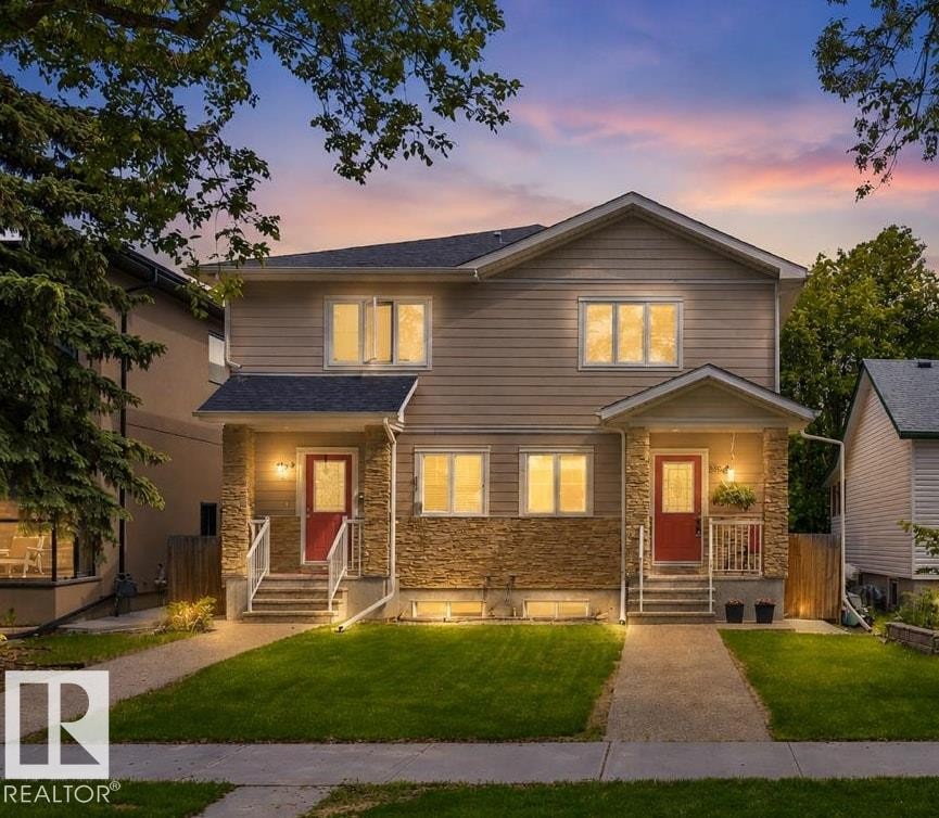 Duplex property featuring a composite shingle roof, stone and siding exterior, red entry doors, white-railed front steps, and landscaped front yards with concrete pathways - 8506 80 Avenue, Edmonton, AB