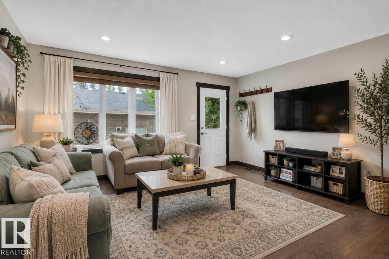 Living area featuring recessed lighting, wood-finish flooring, a prominent window with natural wood trim, and a white paneled door with dark trim - 8506 80 Avenue, Edmonton, AB