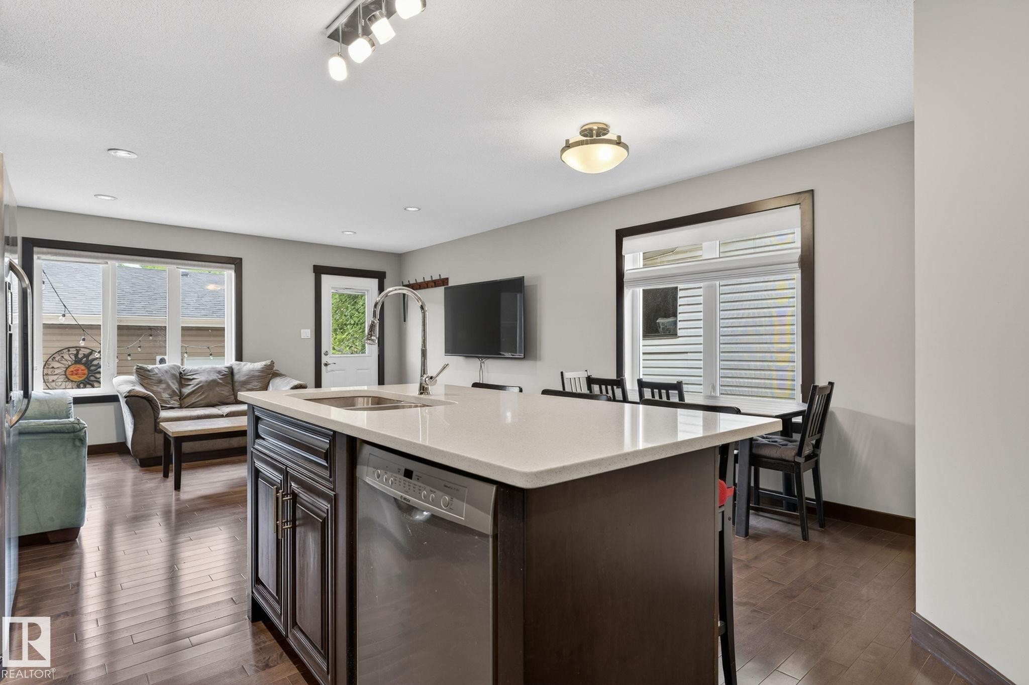 Central kitchen island with a single-basin sink, gooseneck faucet, and integrated stainless steel dishwasher - 8506 80 Avenue, Edmonton, AB