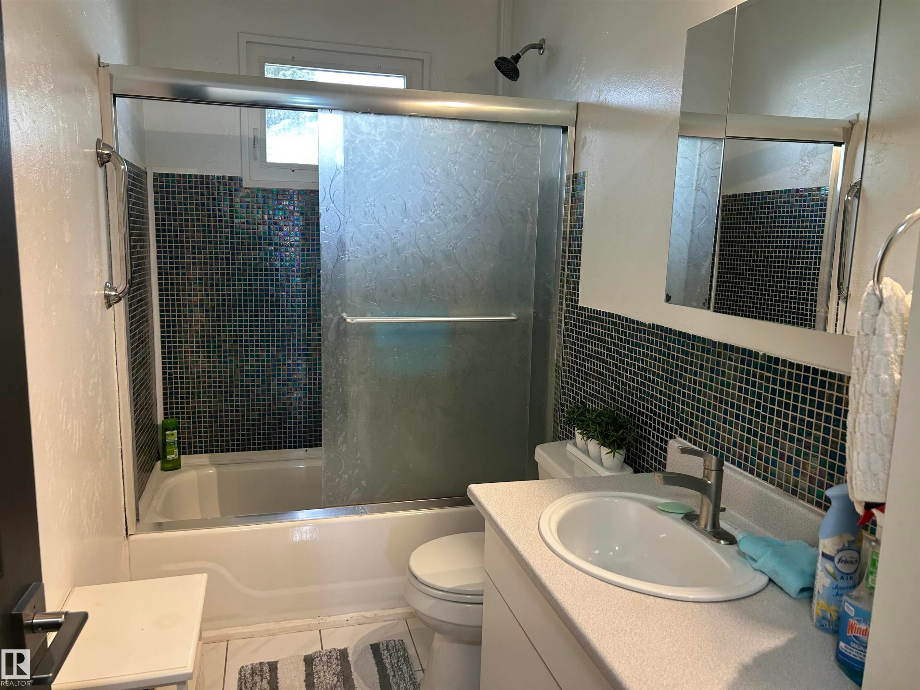 Bathroom with a white bathtub and shower featuring a sliding glass enclosure - 10924 30 Street, Edmonton, AB