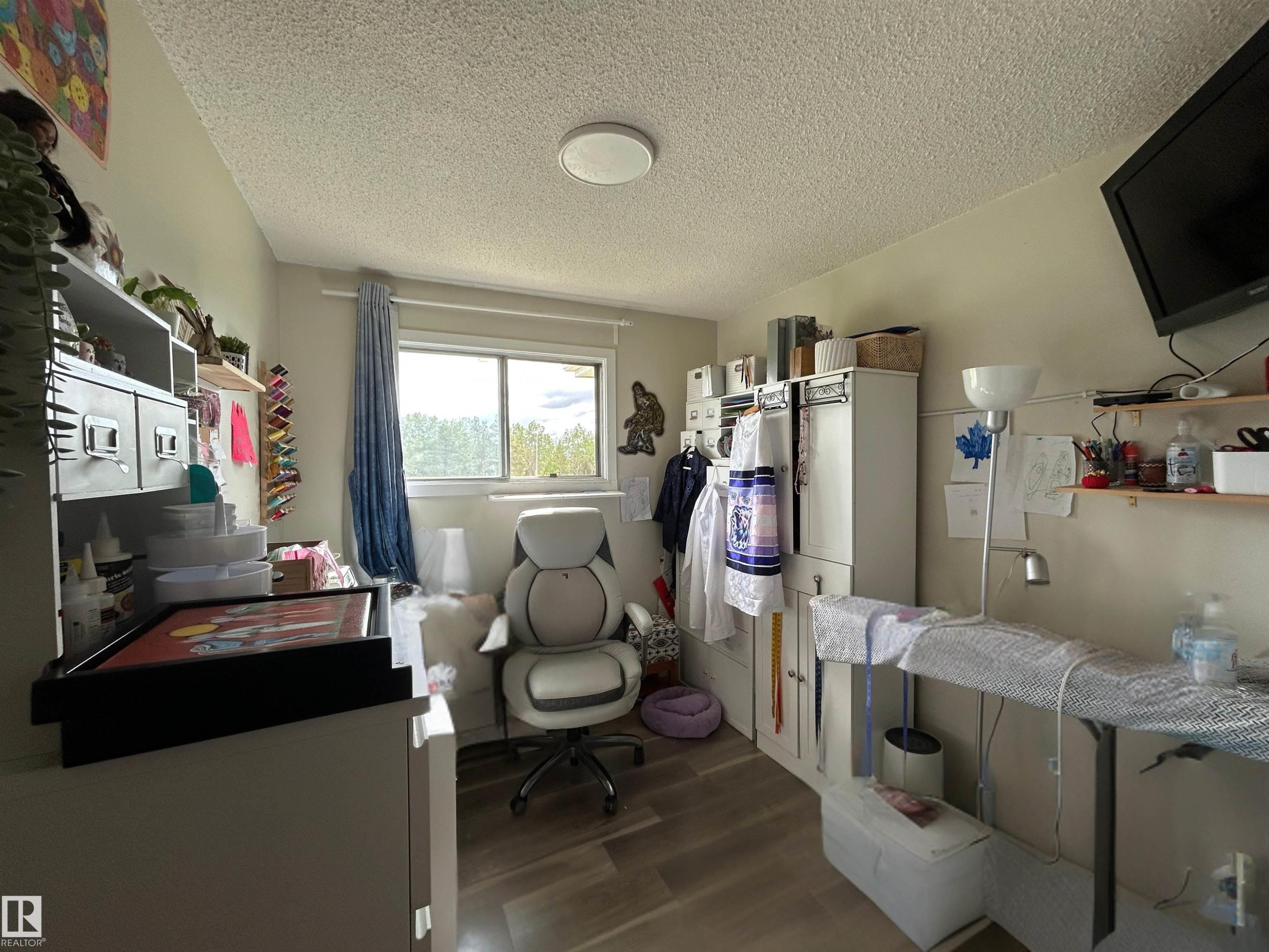 Room featuring wood-finish flooring, a window with natural light, and a ceiling-mounted light fixture - 10924 30 Street, Edmonton, AB