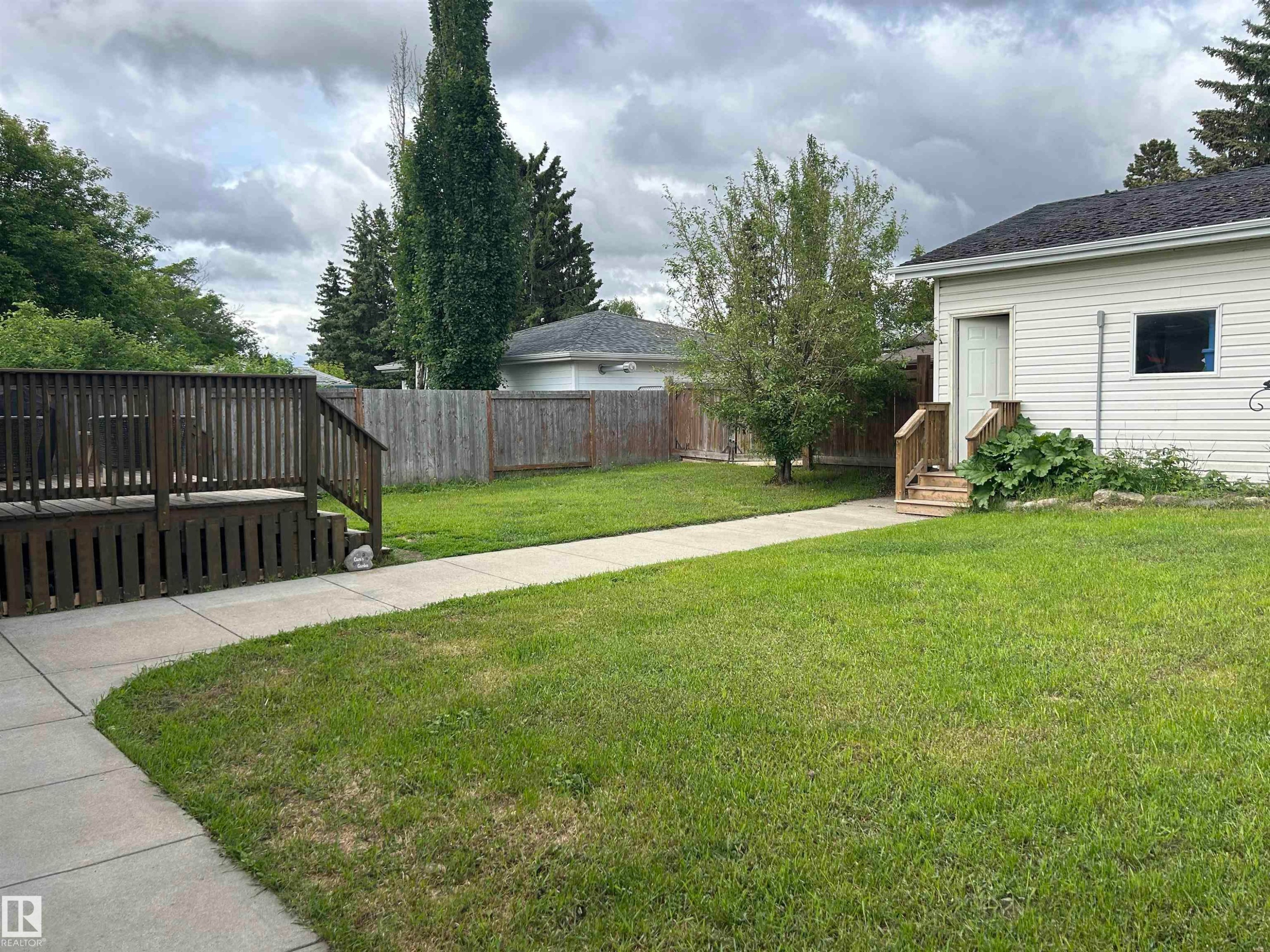 Spacious backyard featuring a wooden deck, a concrete walkway, and a privacy fence - 10924 30 Street, Edmonton, AB