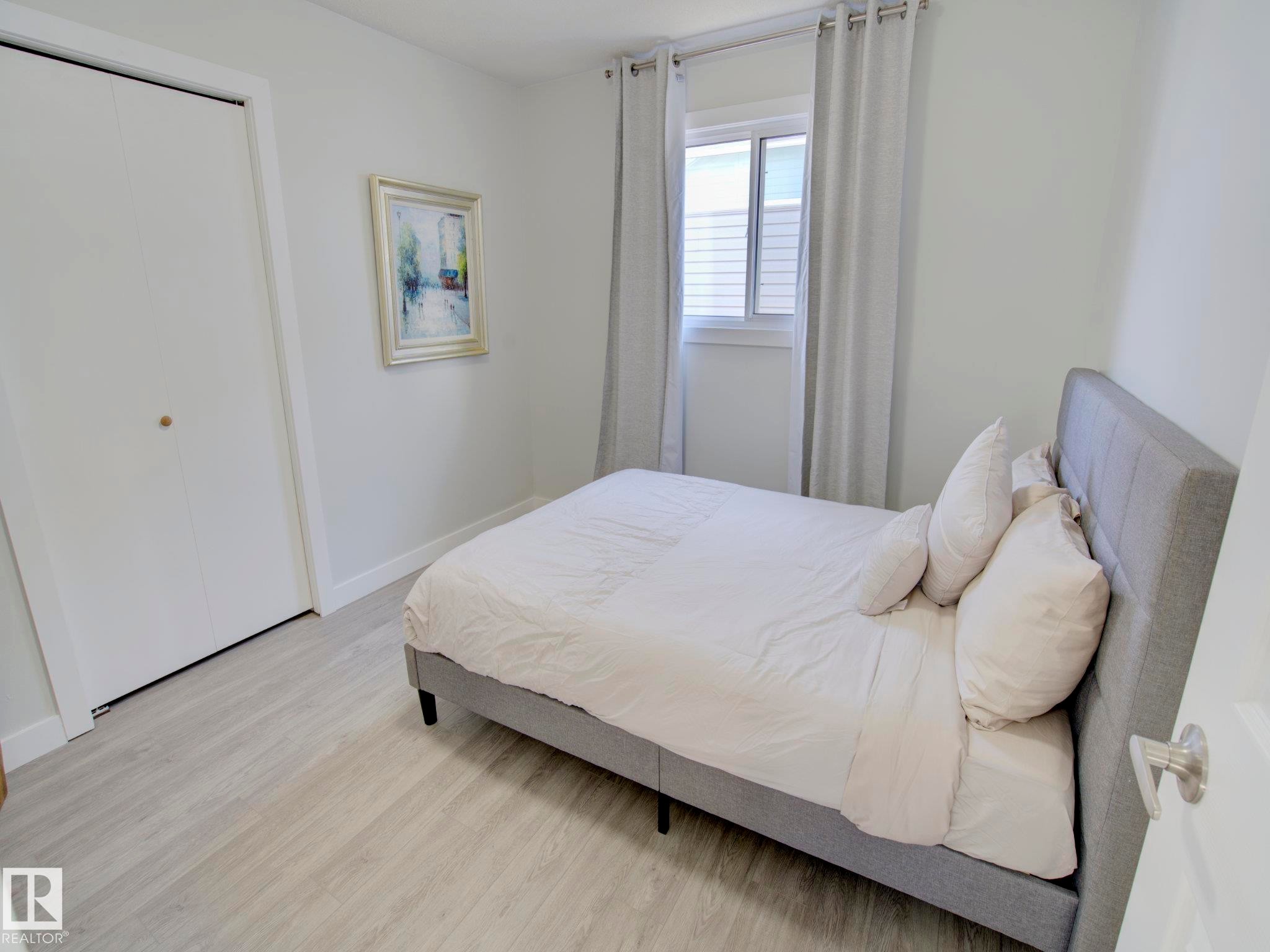 Bedroom featuring light wood-finish flooring, white walls, and a window with natural light - 9909 157 Street, Edmonton, AB