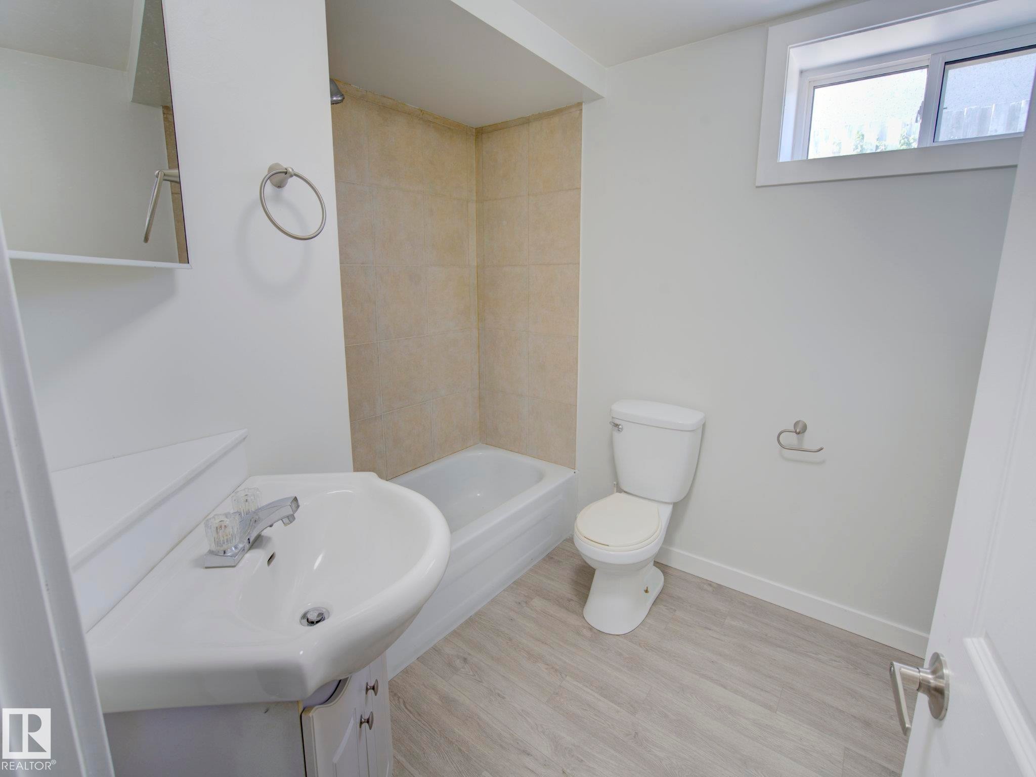 Bathroom featuring a white vanity with integrated sink, chrome faucet, and under-sink storage - 9909 157 Street, Edmonton, AB