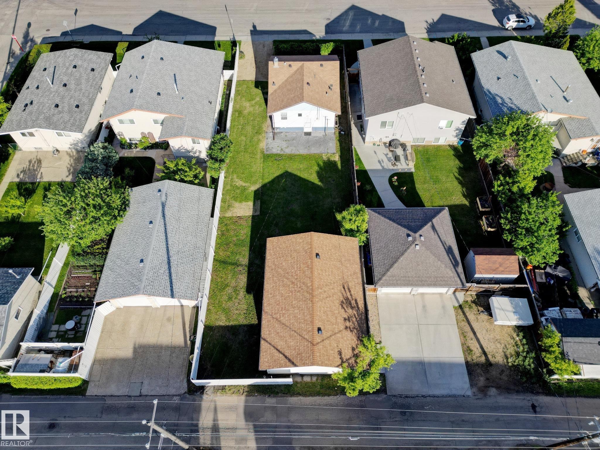 Aerial view of a residential street with multiple homes featuring varied roofing materials, manicured lawns, and paved driveways - 9909 157 Street, Edmonton, AB