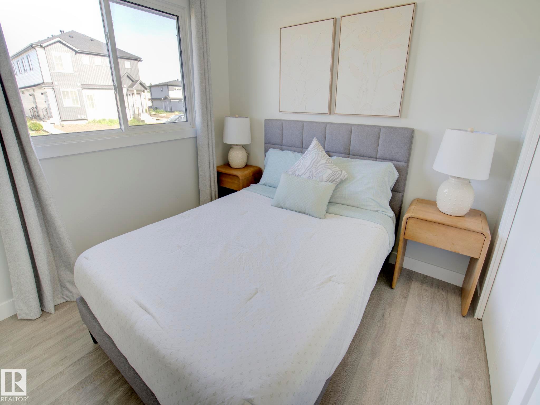 Bright room featuring a large window, light wood-finish flooring, and a neutral color palette - 9909 157 Street, Edmonton, AB