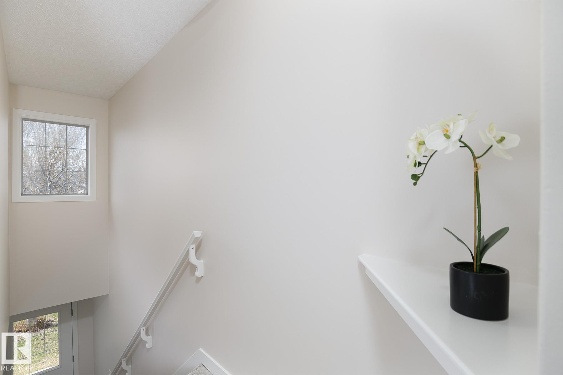 Stairwell with neutral wall paint and a gridded window - #55 14603 Miller Bv Nw, Edmonton, AB