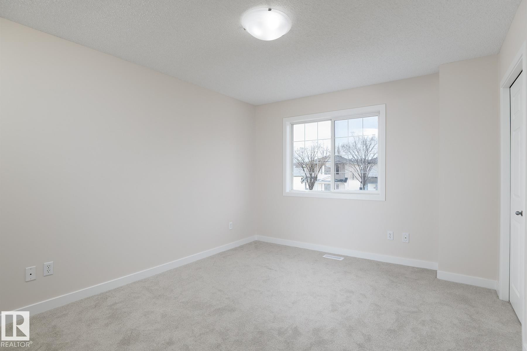 Spacious room featuring neutral paint, light gray carpeting, and a white window frame - #55 14603 Miller Bv Nw, Edmonton, AB