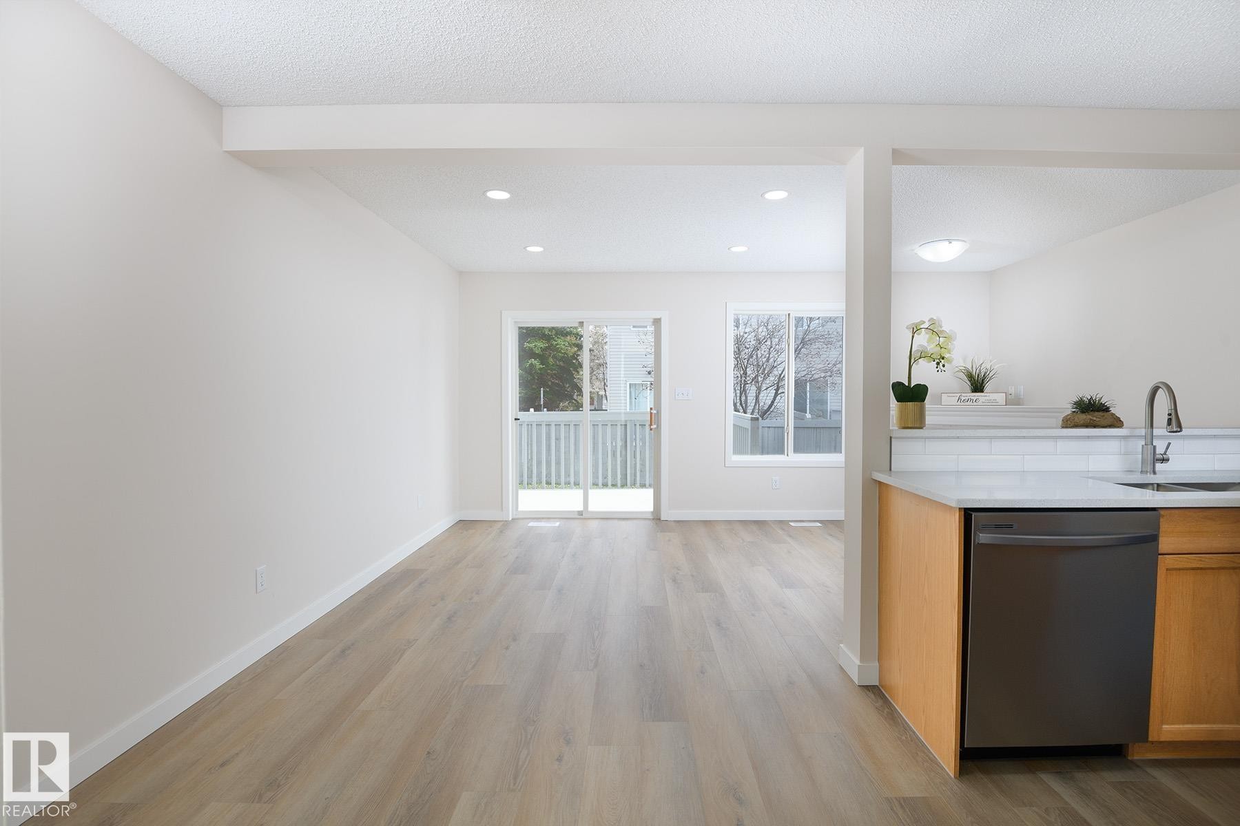 Open-concept living space featuring wood-finish flooring, recessed lighting, and a sliding glass door leading to a deck - #55 14603 Miller Bv Nw, Edmonton, AB