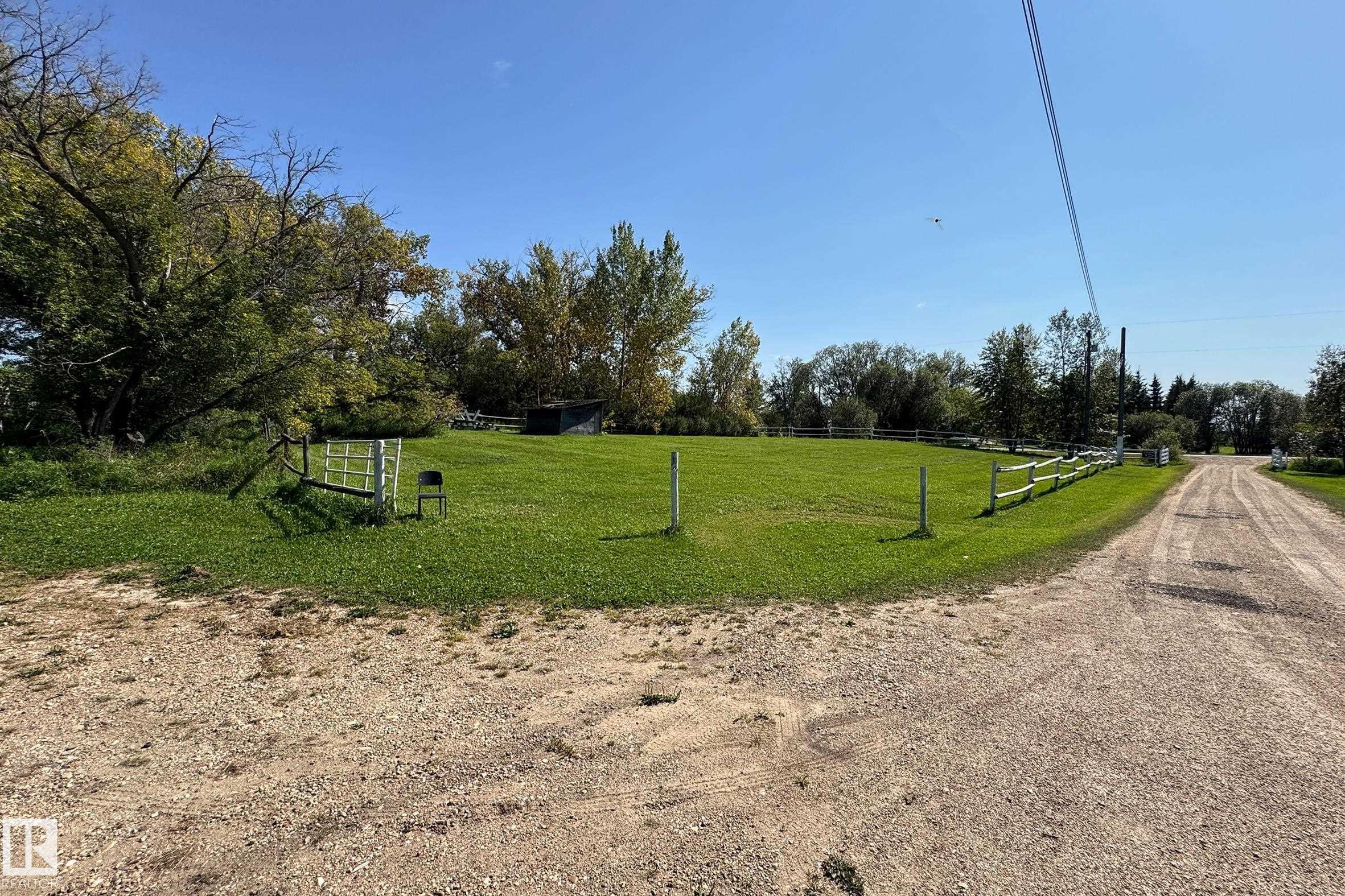 Expansive green lawn with mature trees and a partial wood rail fence - 3054 28 Avenue, Edmonton, AB