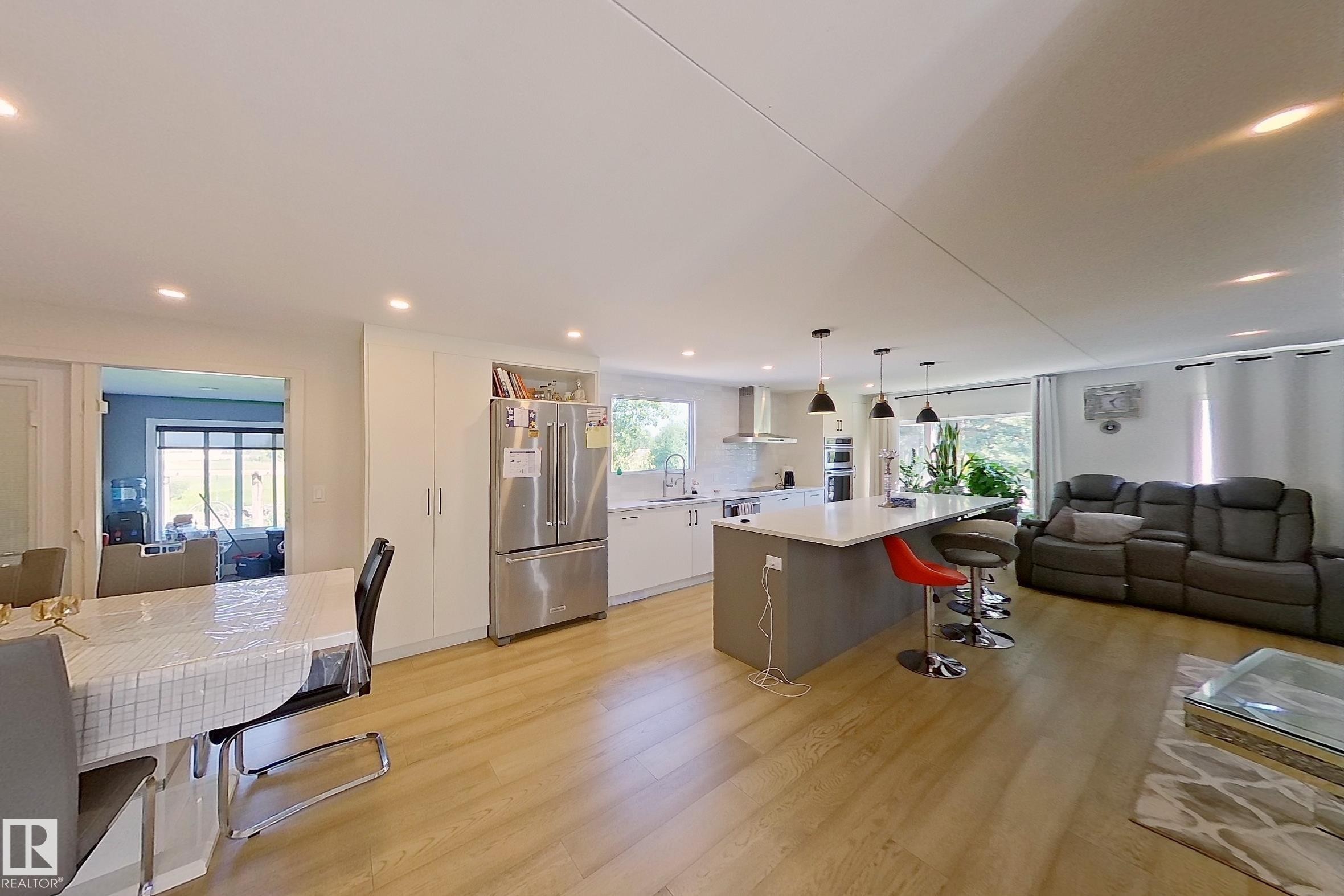 Open-concept living space featuring wood-finish flooring, recessed lighting, and a kitchen island with pendant lights - 3054 28 Avenue, Edmonton, AB