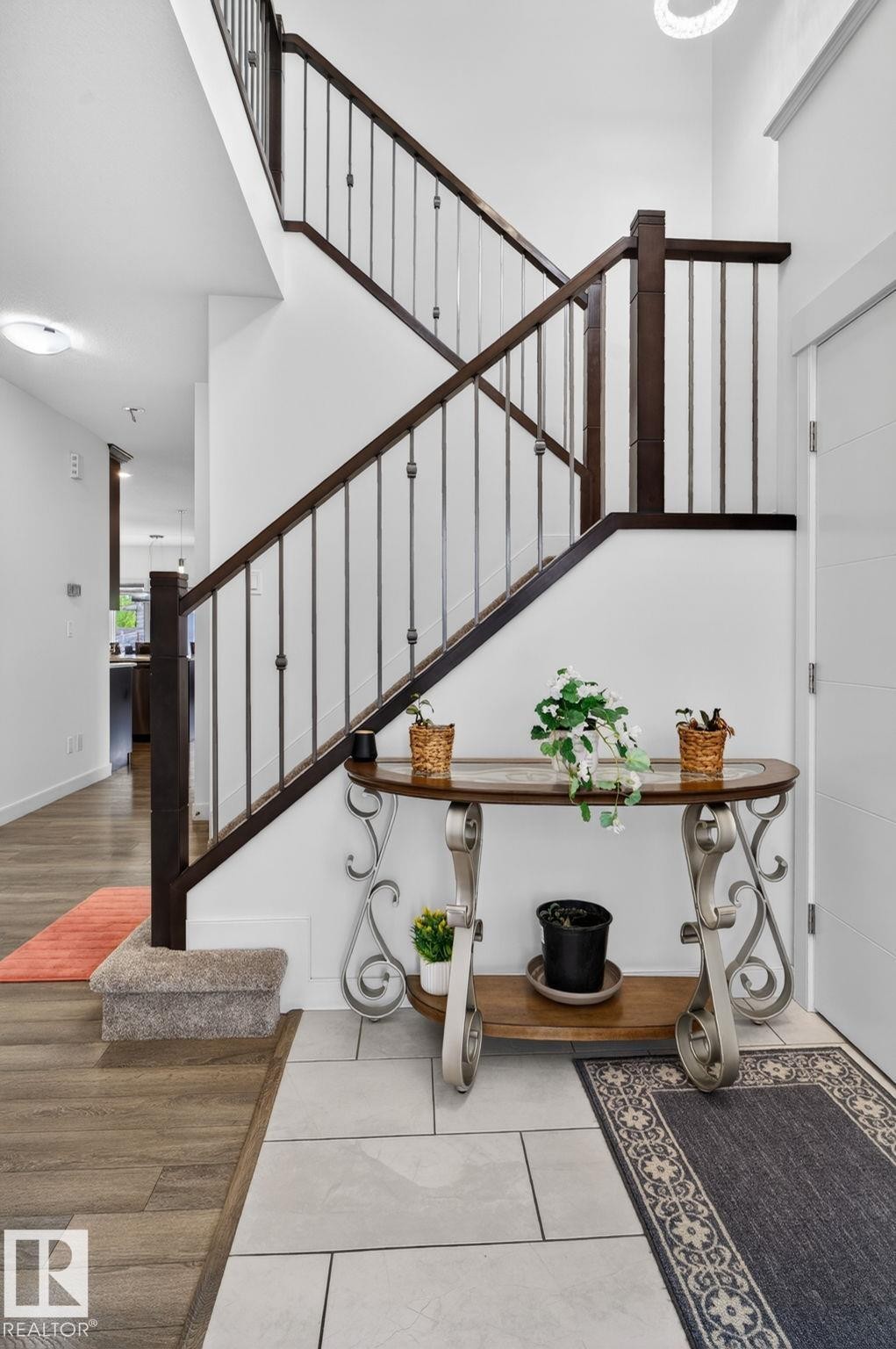 Grand staircase featuring dark wood newel posts and handrails with iron balusters - 704 39 Street, Edmonton, AB