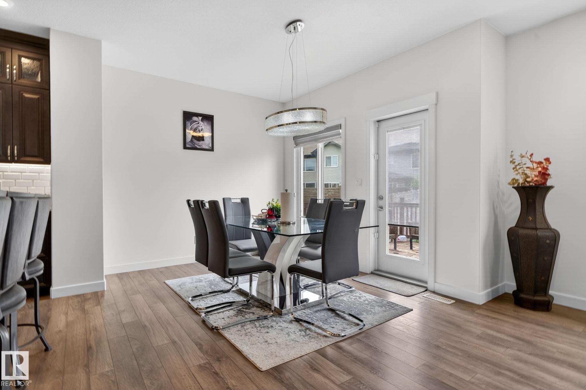 Dining area featuring wood-finish flooring and a contemporary chandelier - 704 39 Street, Edmonton, AB
