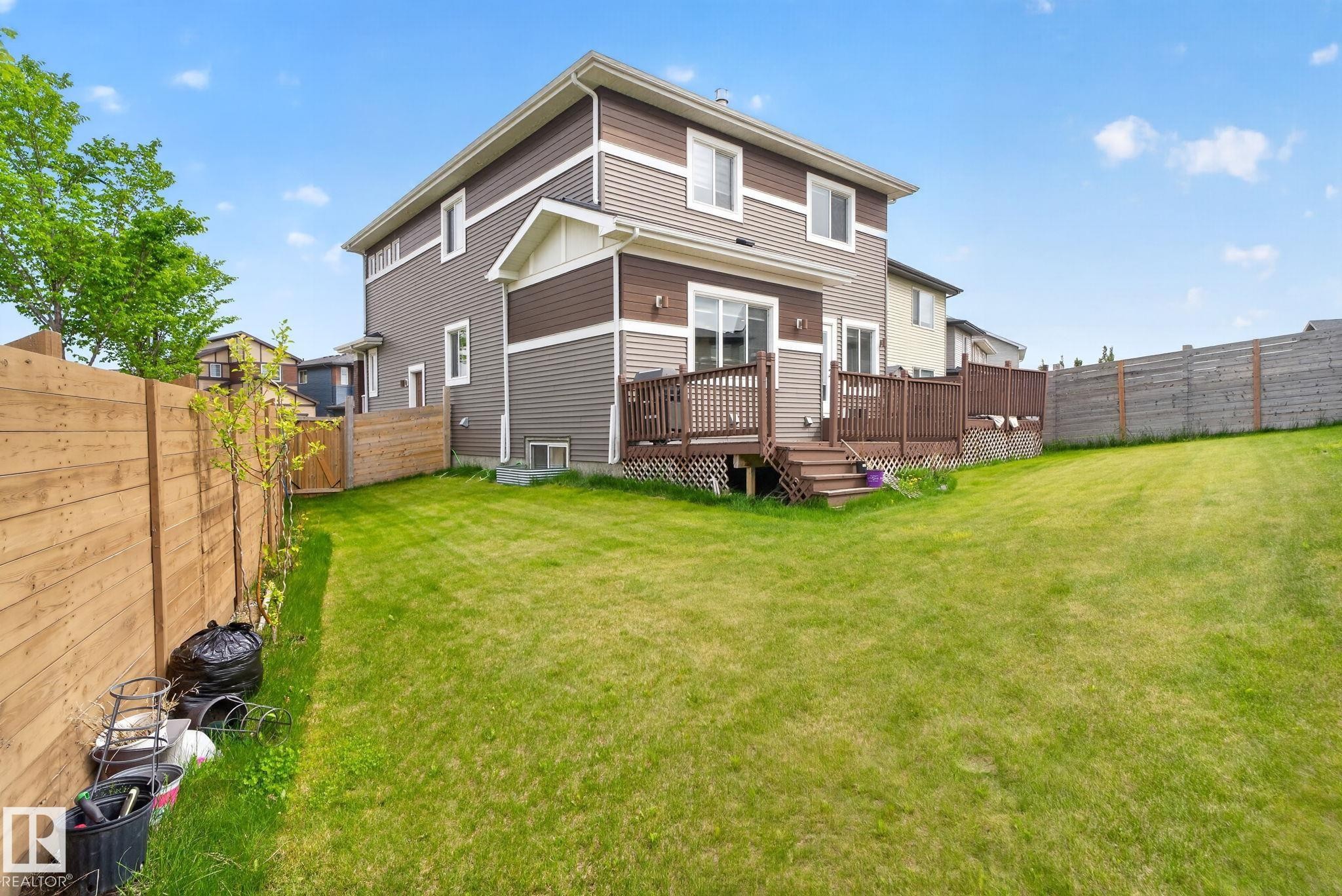 Multi-level exterior with siding, a large wooden deck, expansive lawn, and full privacy fencing - 704 39 Street, Edmonton, AB