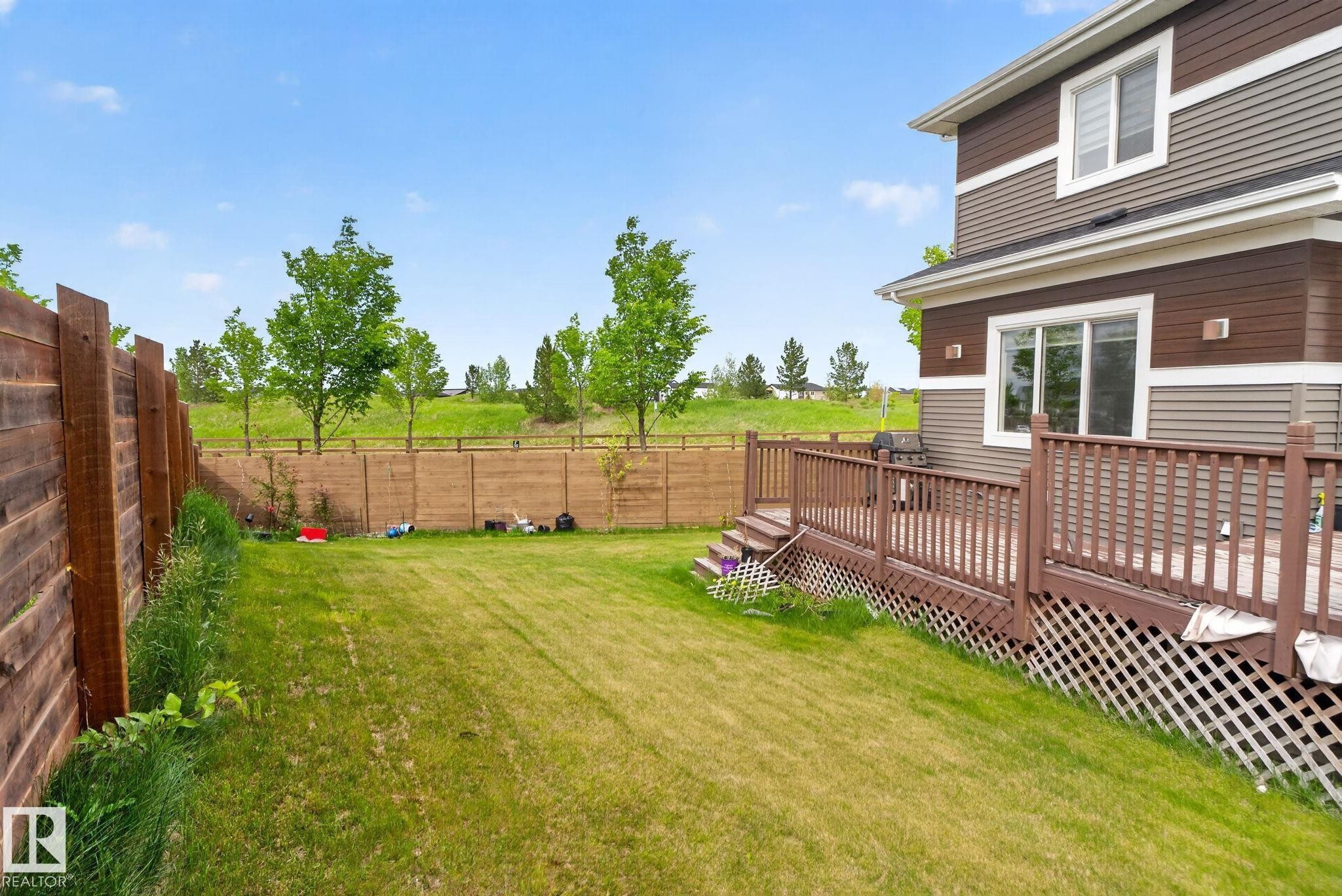 Expansive backyard featuring a manicured lawn, a multi-level wood deck with lattice skirting, and a horizontal wood fence - 704 39 Street, Edmonton, AB