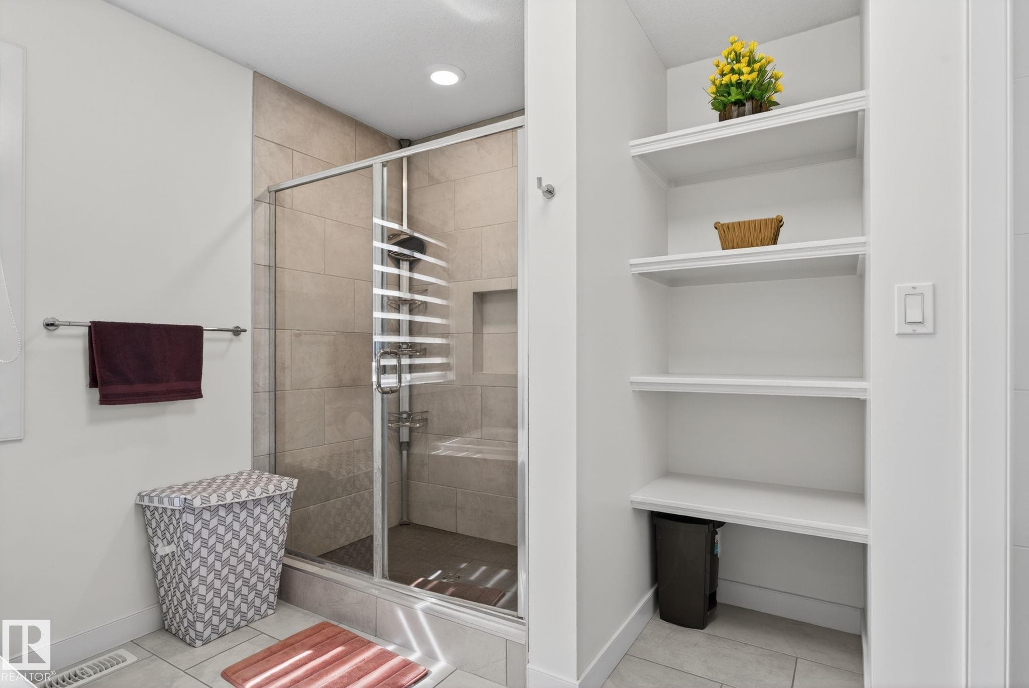 Glass-enclosed shower with tiled walls and floor, featuring a built-in shower niche - 704 39 Street, Edmonton, AB