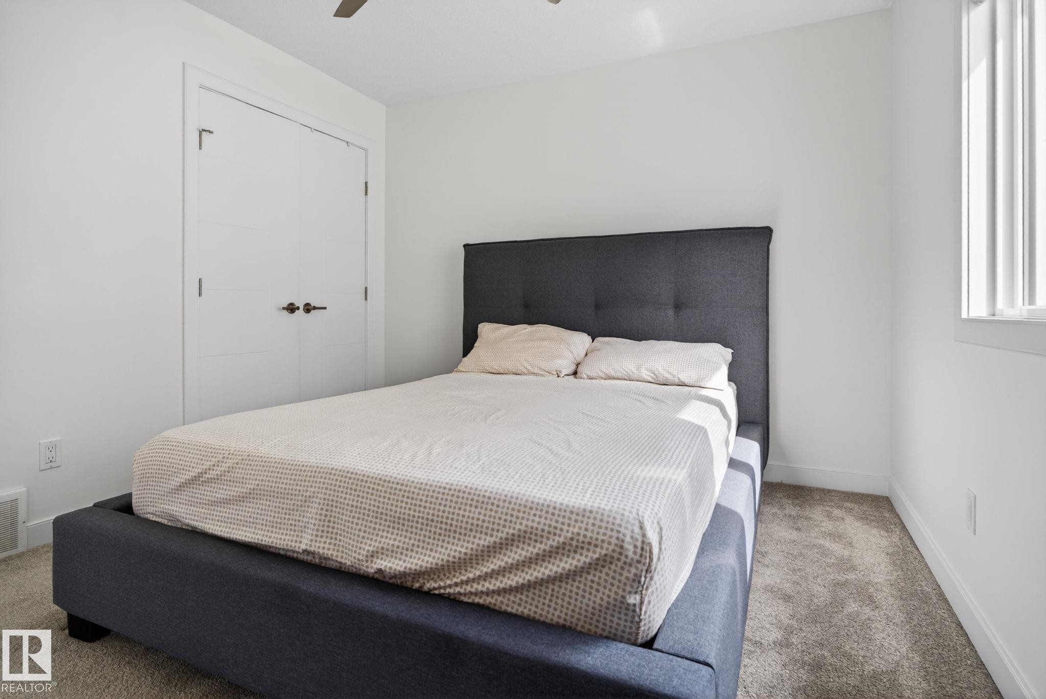 Bedroom featuring light gray carpet flooring, white baseboards, and a white window with vertical blinds - 704 39 Street, Edmonton, AB