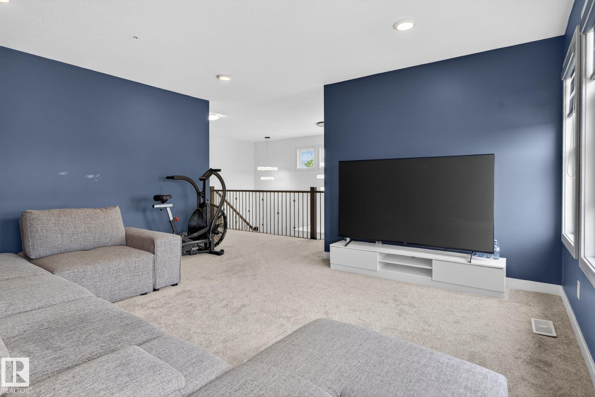 Spacious upper-level area featuring a vibrant accent wall, recessed lighting, and soft carpeting - 704 39 Street, Edmonton, AB