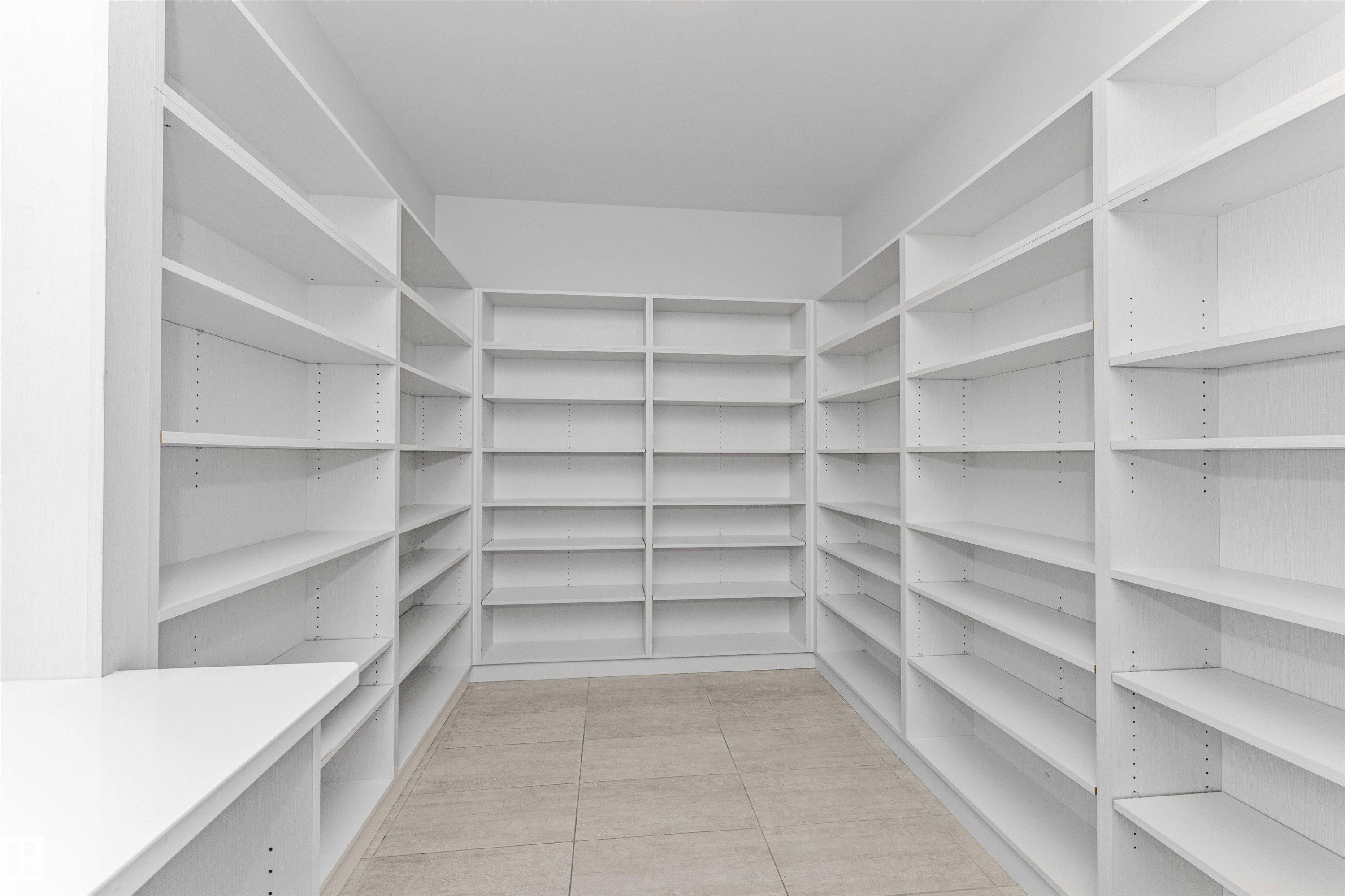 Dedicated storage room featuring extensive built-in white shelving, a built-in white countertop, and light-toned tile flooring - 3310 Watson Bay, Edmonton, AB