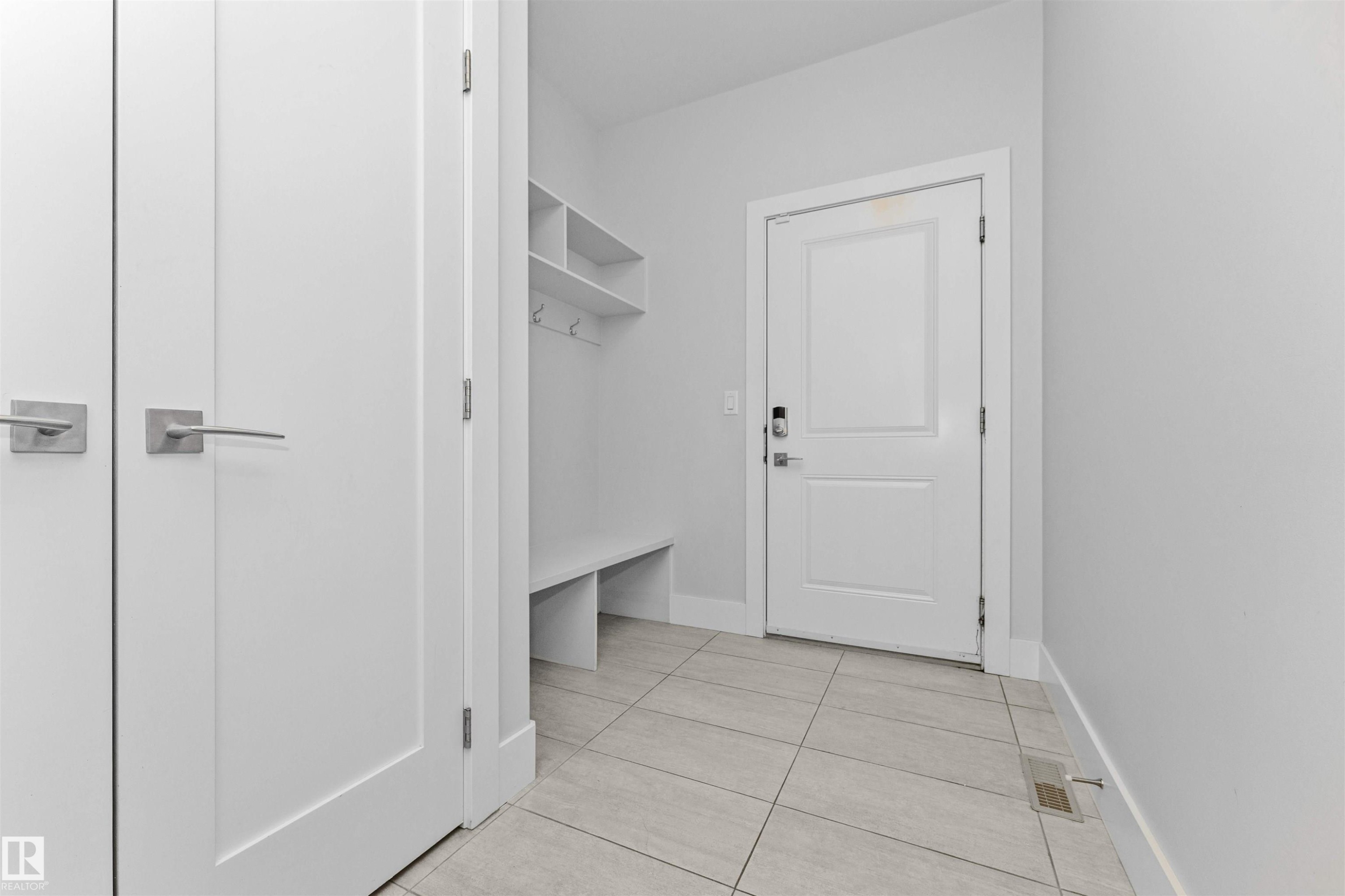 Entryway featuring light-toned tile flooring and a built-in storage bench with shelving and coat hooks - 3310 Watson Bay, Edmonton, AB