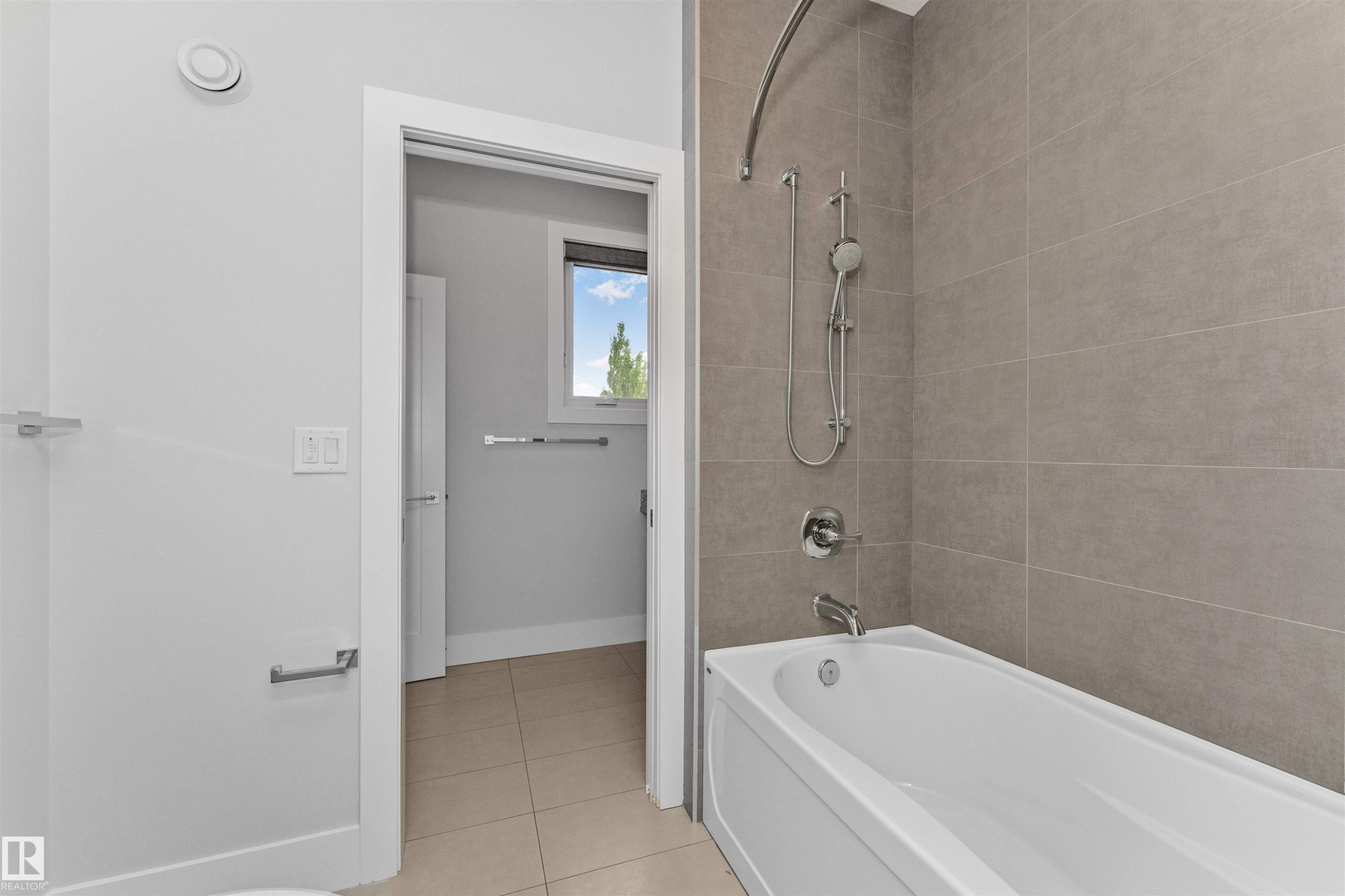 Contemporary bathroom featuring a white bathtub with chrome fixtures and light-toned tile surround - 3310 Watson Bay, Edmonton, AB
