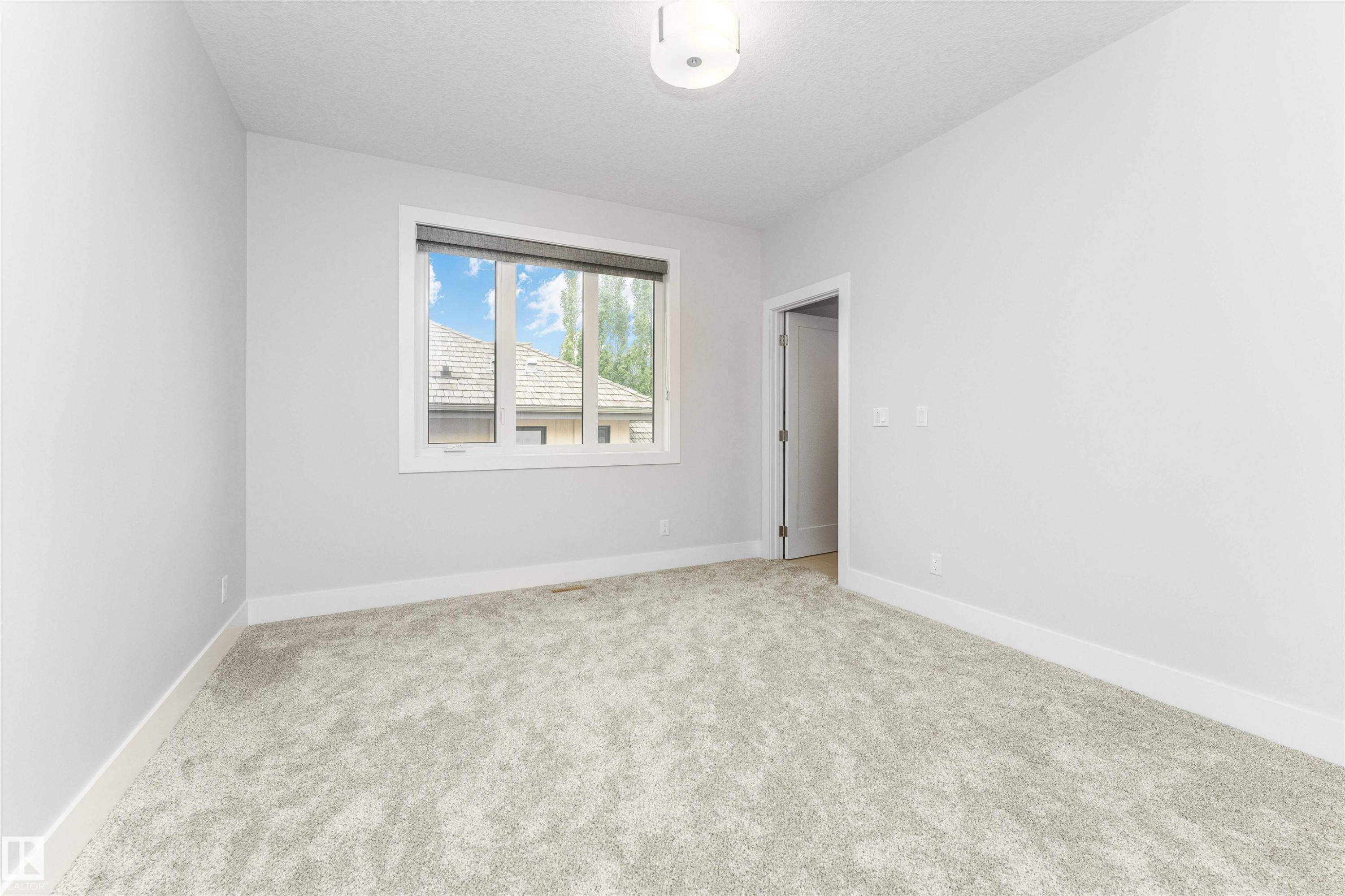 Neutral-toned room featuring light gray carpeting, white baseboards, and a white ceiling with a flush-mount light fixture - 3310 Watson Bay, Edmonton, AB