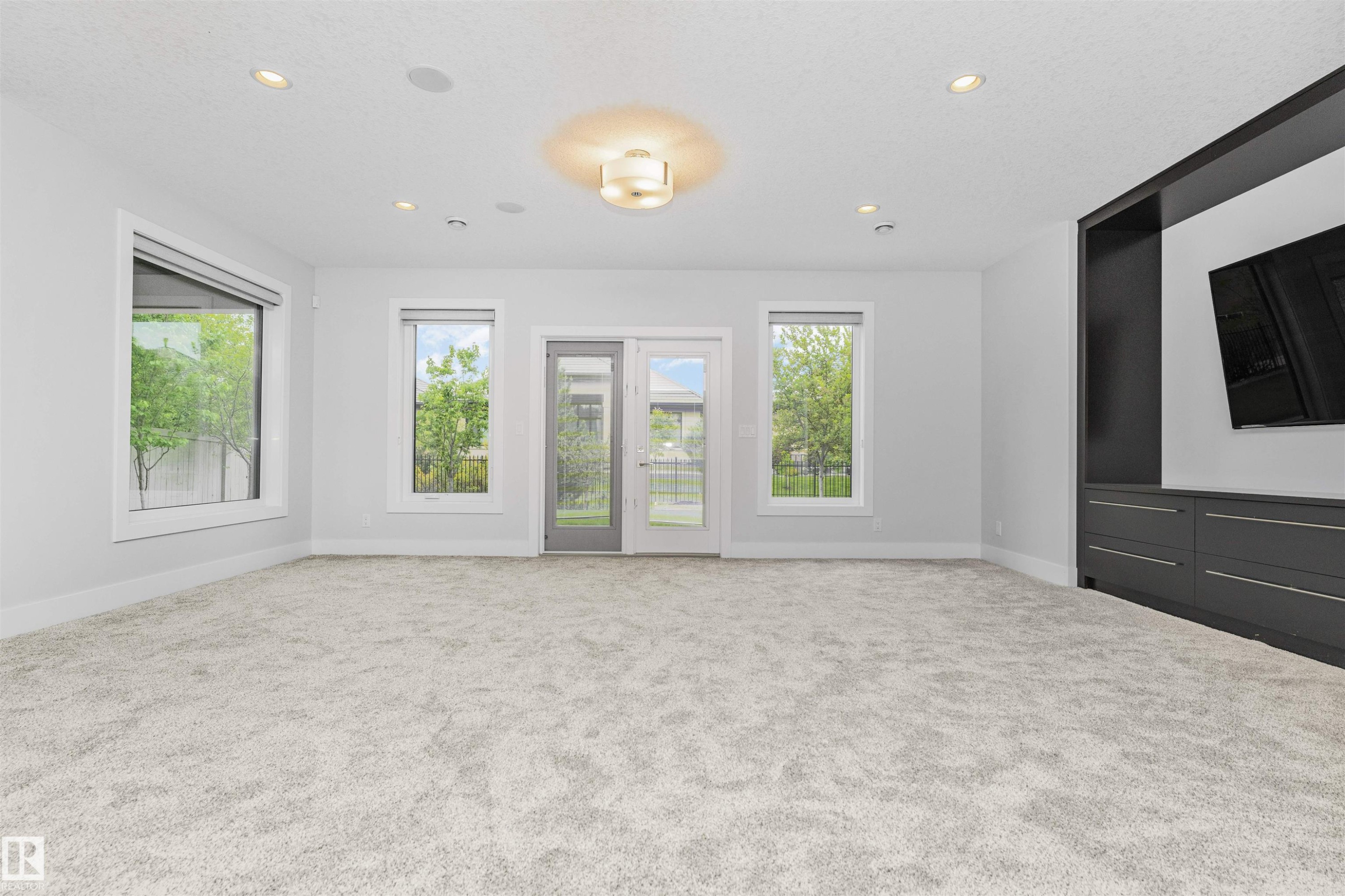 Spacious room featuring plush carpeting, a built-in entertainment center with integrated storage, and multiple windows - 3310 Watson Bay, Edmonton, AB