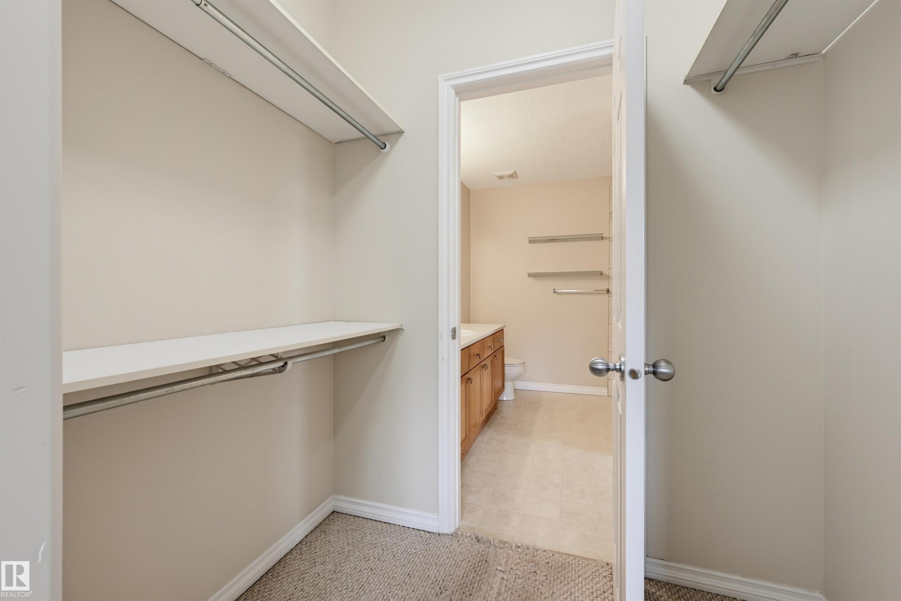 Walk-in closet with carpet flooring, white shelving, and chrome hanging rods - 203 10719 80 Avenue, Edmonton, AB