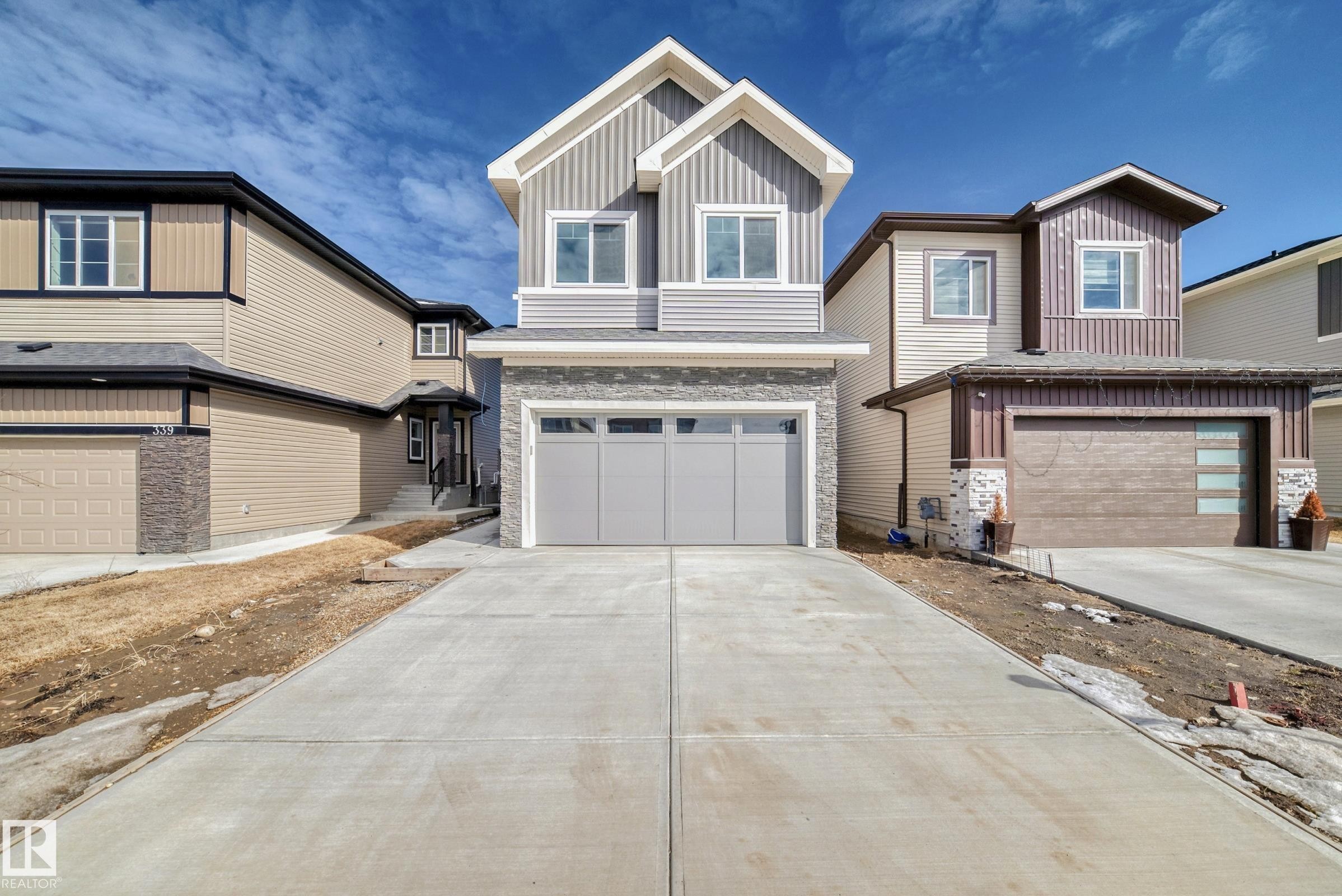 Contemporary two-story residence featuring light gray siding and stone accents - 341 Roberts Wynd, Leduc, AB