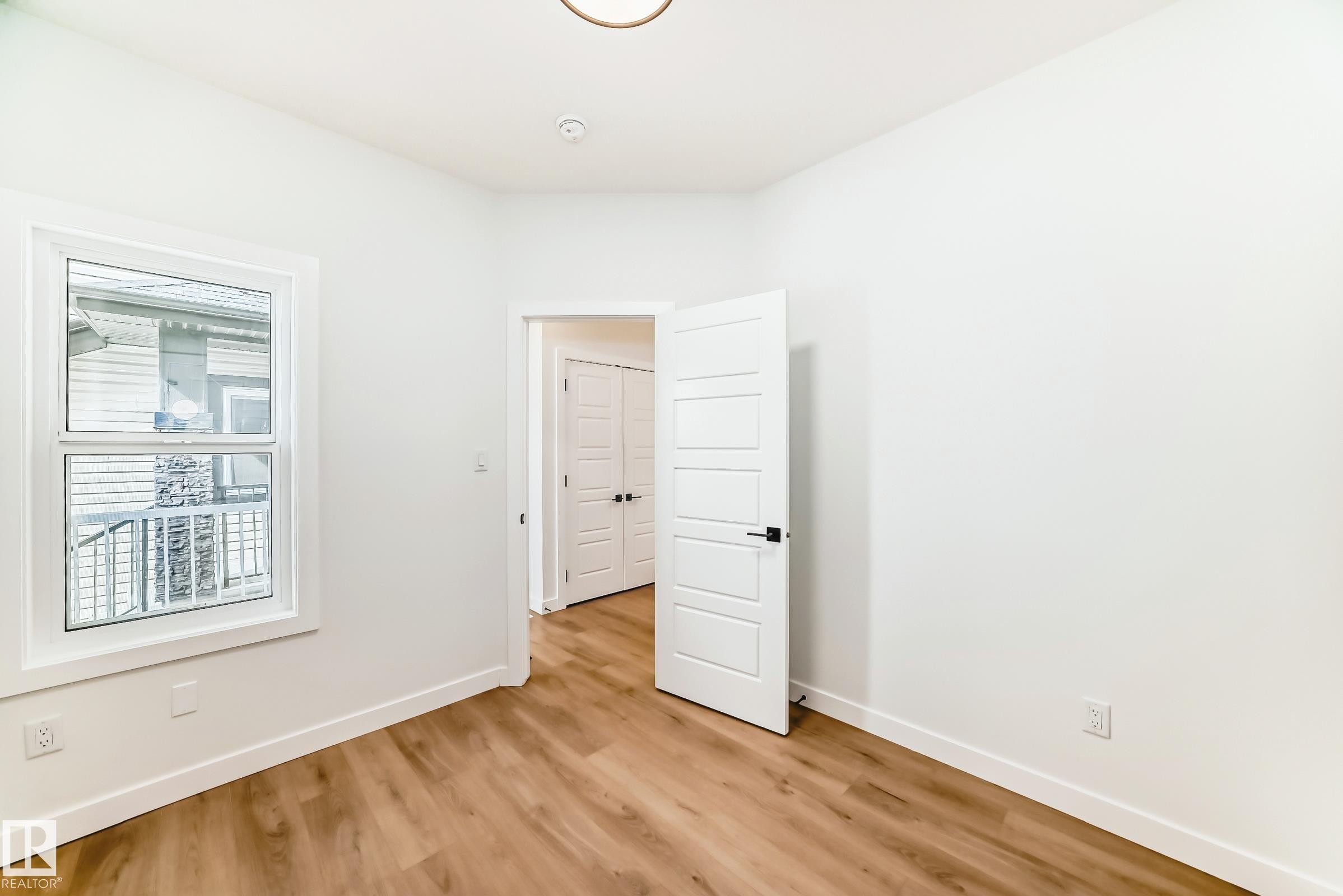 Room featuring wood-finish flooring, white baseboards, and a single window with white trim - 341 Roberts Wynd, Leduc, AB