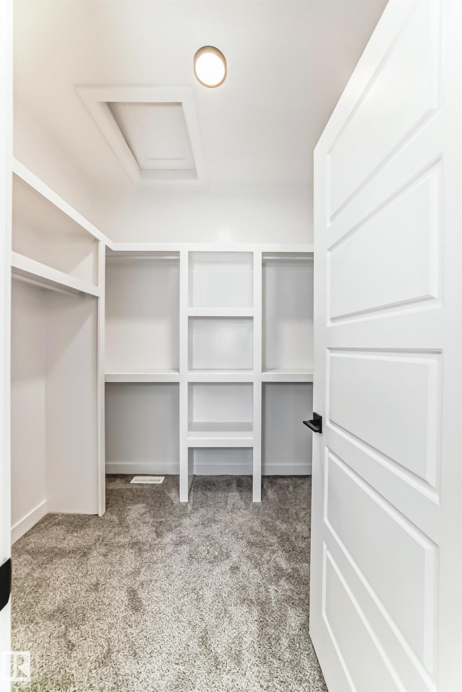 Walk-in closet featuring white built-in shelving, hanging rods, recessed ceiling lighting, and gray carpeting - 341 Roberts Wynd, Leduc, AB