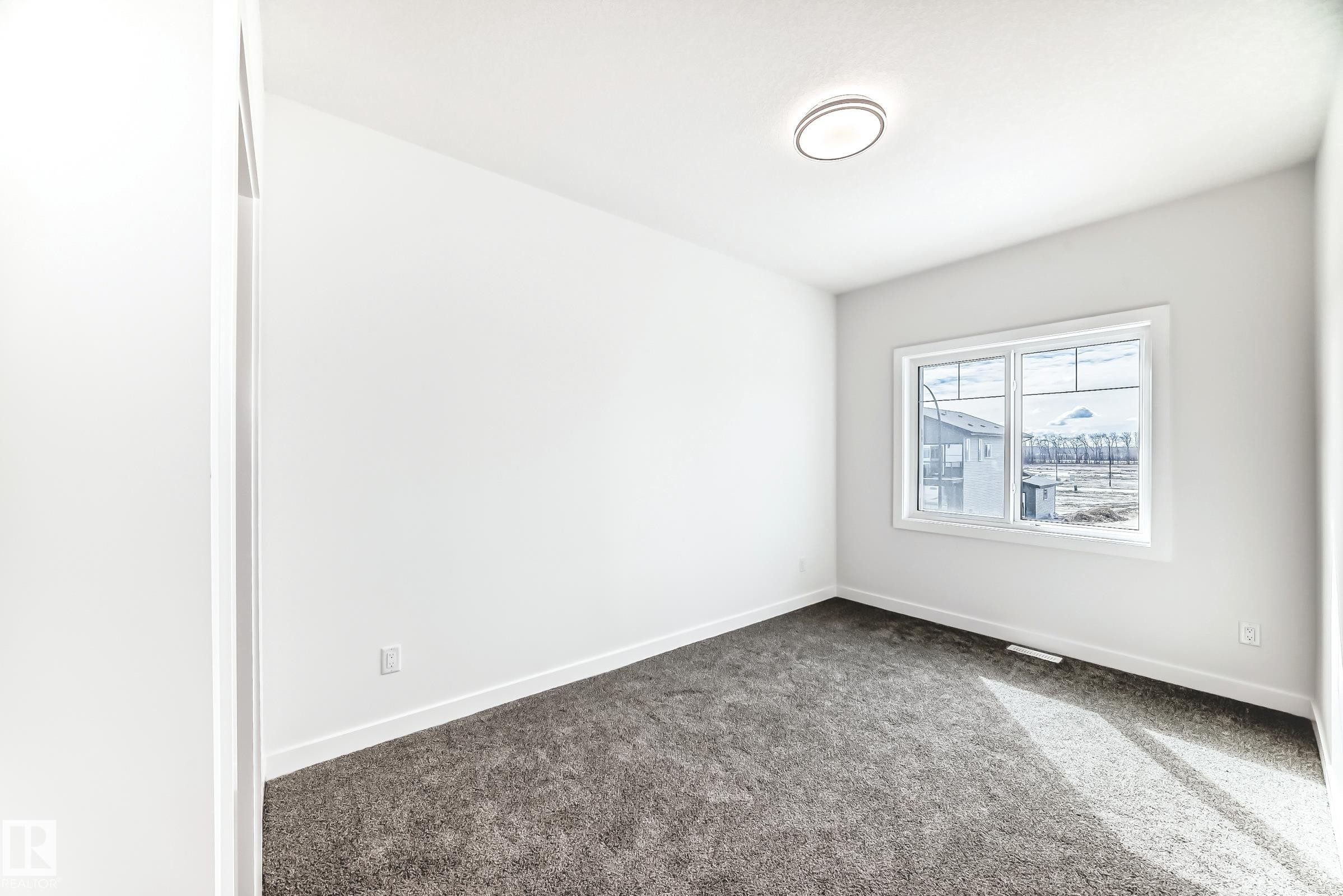 Bright interior space featuring a window with white trim, plush gray carpeting, and a flush-mount ceiling light fixture - 341 Roberts Wynd, Leduc, AB
