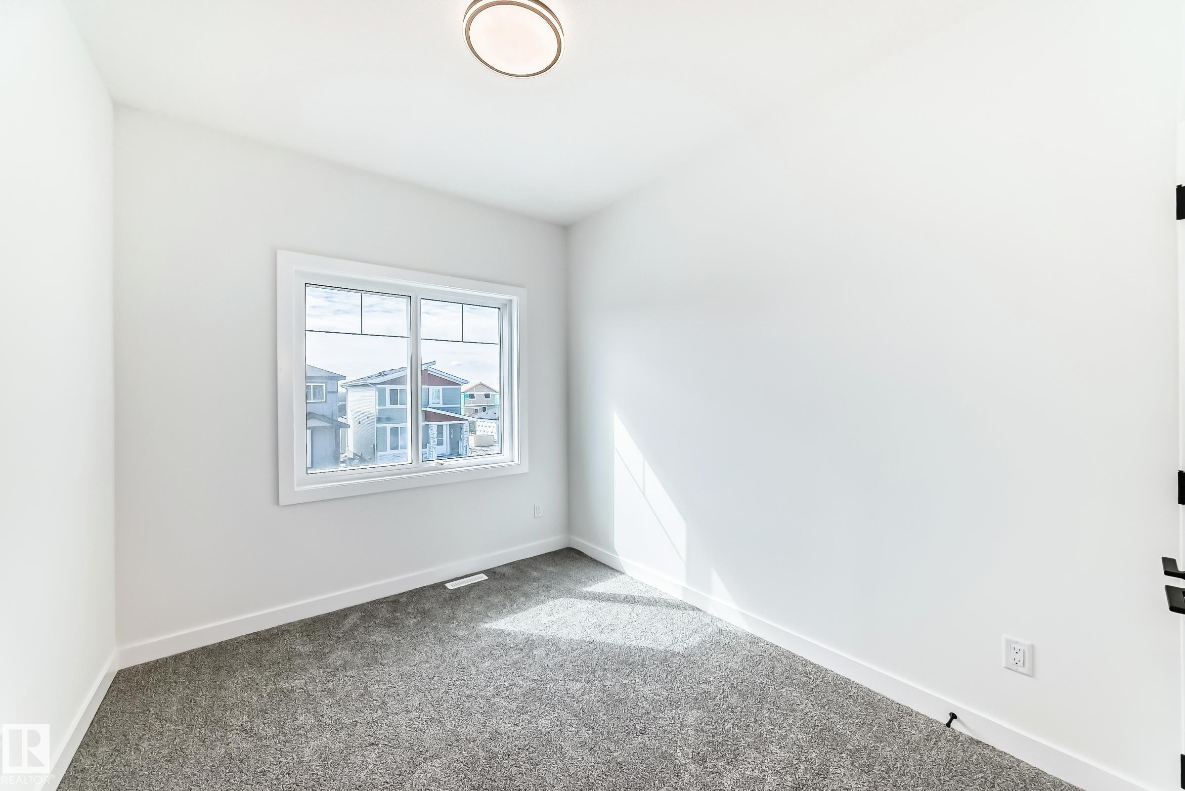 Bright room featuring light gray carpet, white walls, and a modern flush-mount ceiling light - 341 Roberts Wynd, Leduc, AB