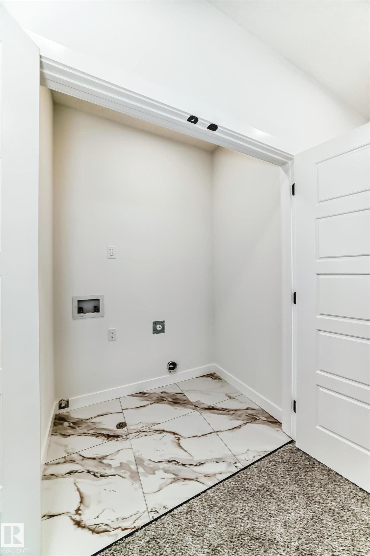 Dedicated laundry closet featuring white and brown veined tile flooring, white baseboards, and white walls - 341 Roberts Wynd, Leduc, AB