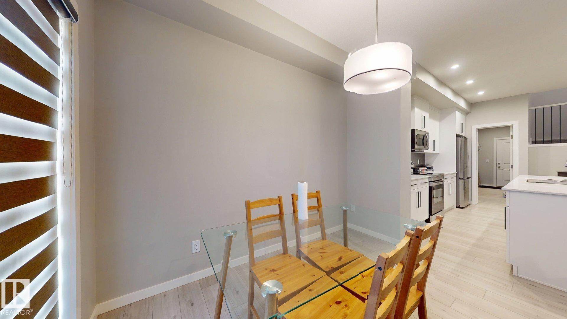 Dining area featuring a contemporary drum pendant light and durable wood-finish flooring - 607 31 Avenue, Edmonton, AB