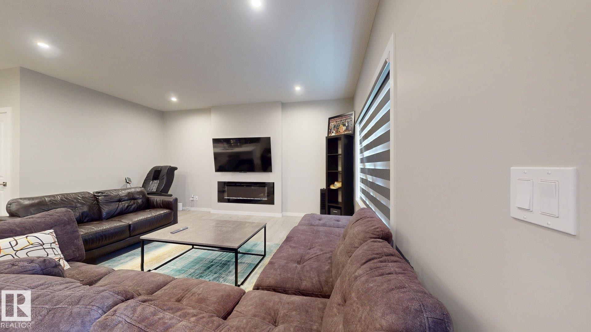 Living area featuring a modern fireplace insert, recessed lighting, light-toned walls, and wood-finish flooring - 607 31 Avenue, Edmonton, AB