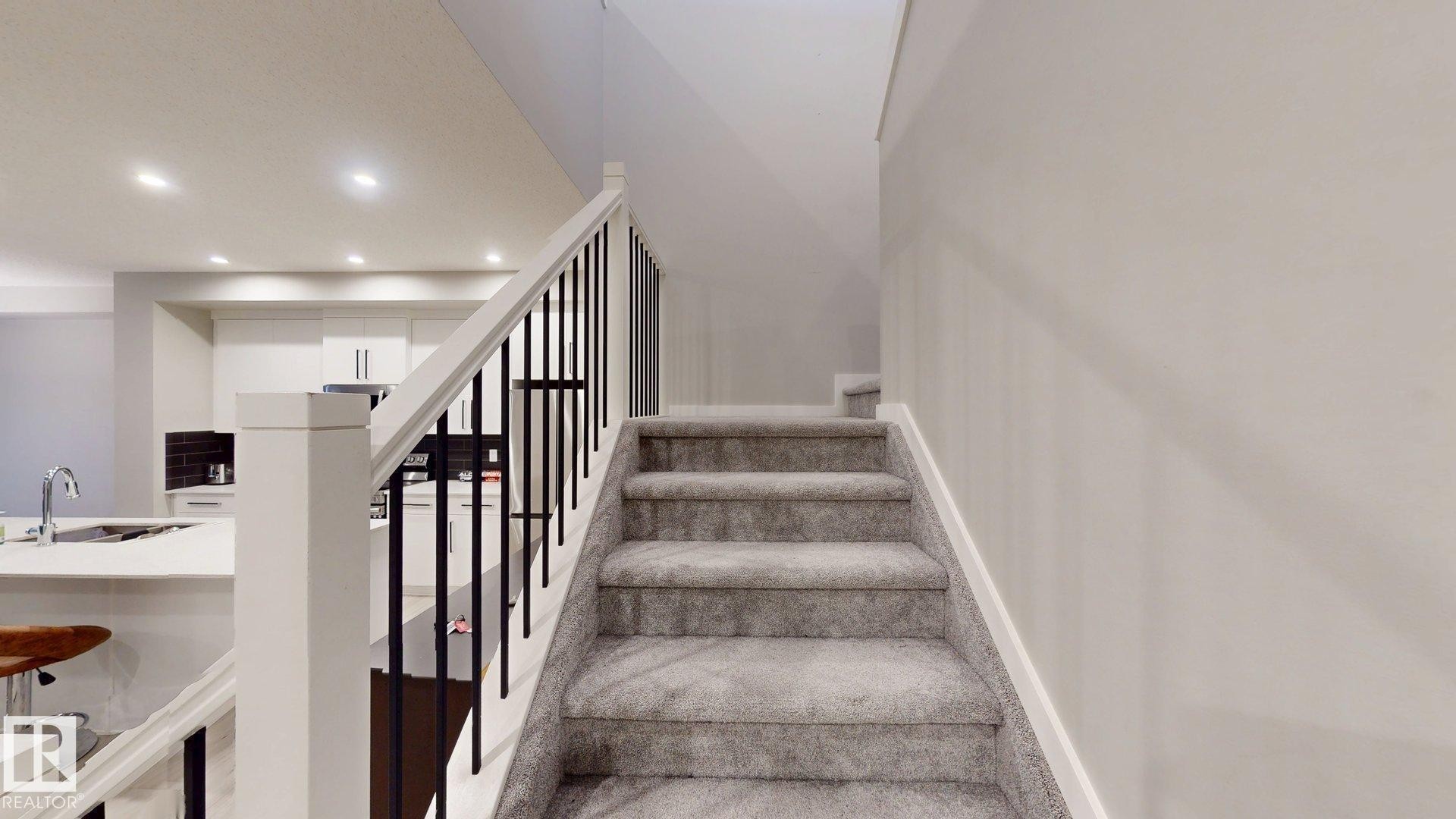 Carpeted staircase with white newel posts and black metal balusters - 607 31 Avenue, Edmonton, AB
