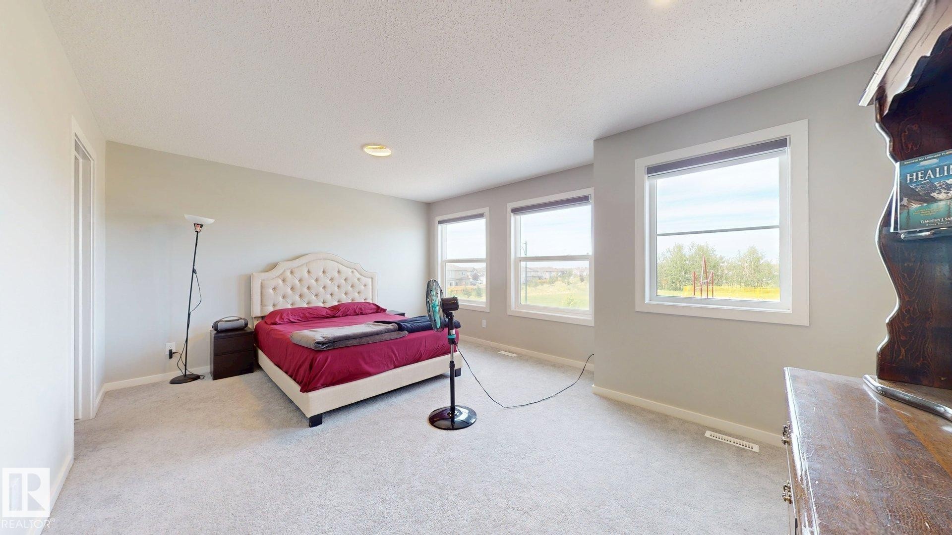 Spacious room featuring light gray carpeting, neutral wall finishes, multiple windows with white trim, and recessed lighting - 607 31 Avenue, Edmonton, AB