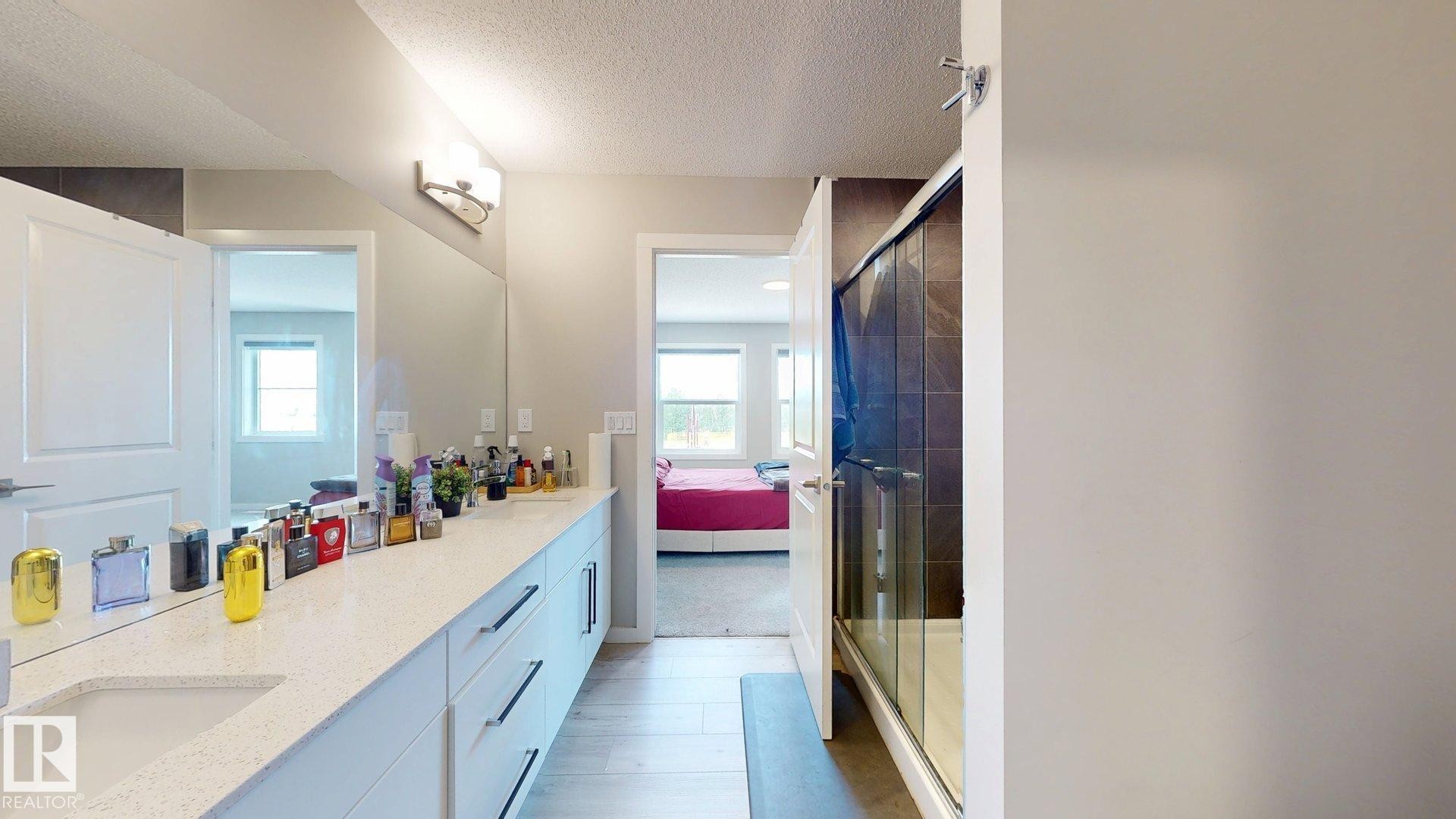 Bathroom featuring a double vanity with stone countertops, integrated sinks, and ample storage cabinetry - 607 31 Avenue, Edmonton, AB