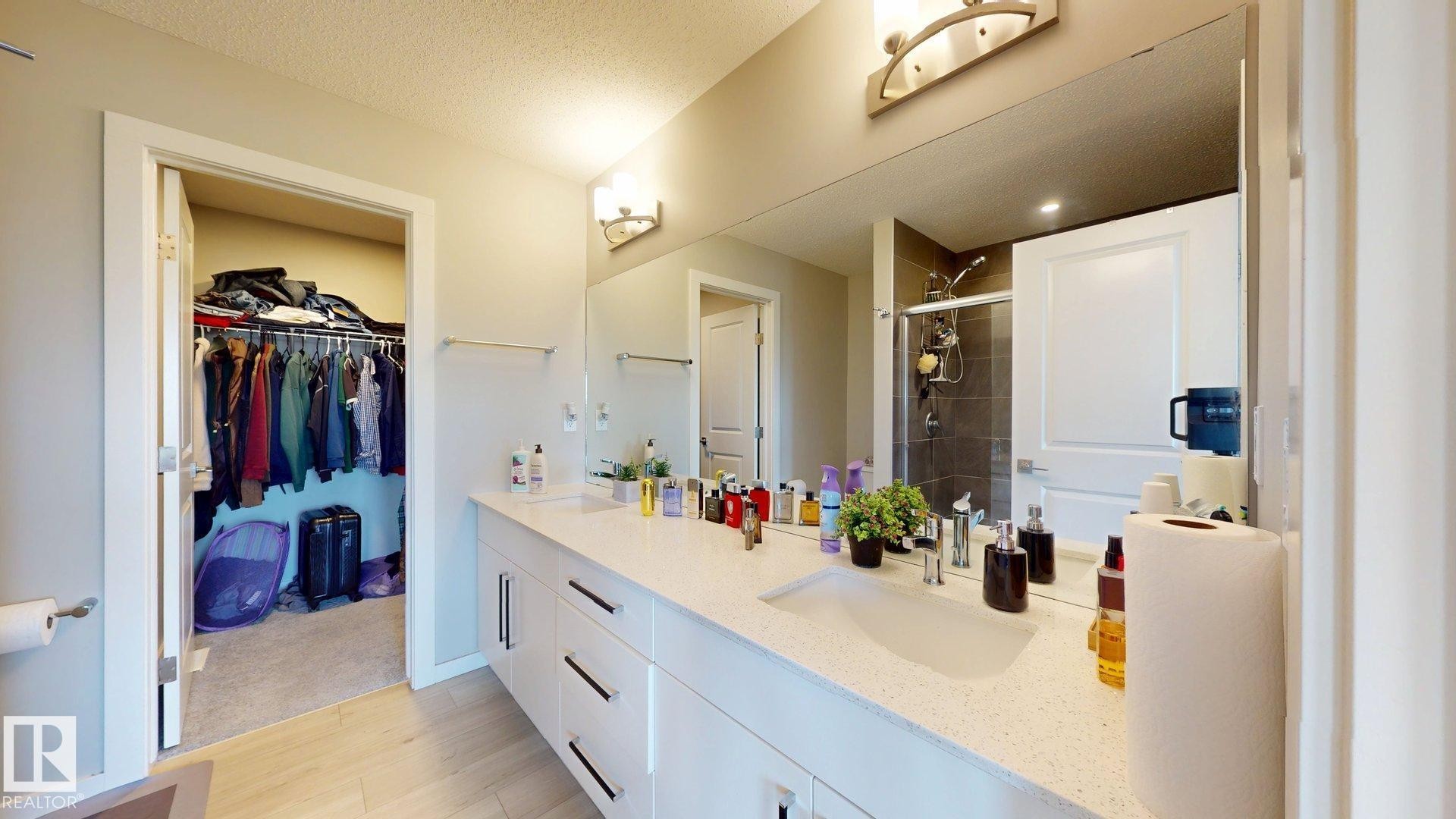 Bathroom vanity featuring dual sinks with integrated countertops, contemporary cabinet hardware, and a large wall-mounted mirror - 607 31 Avenue, Edmonton, AB
