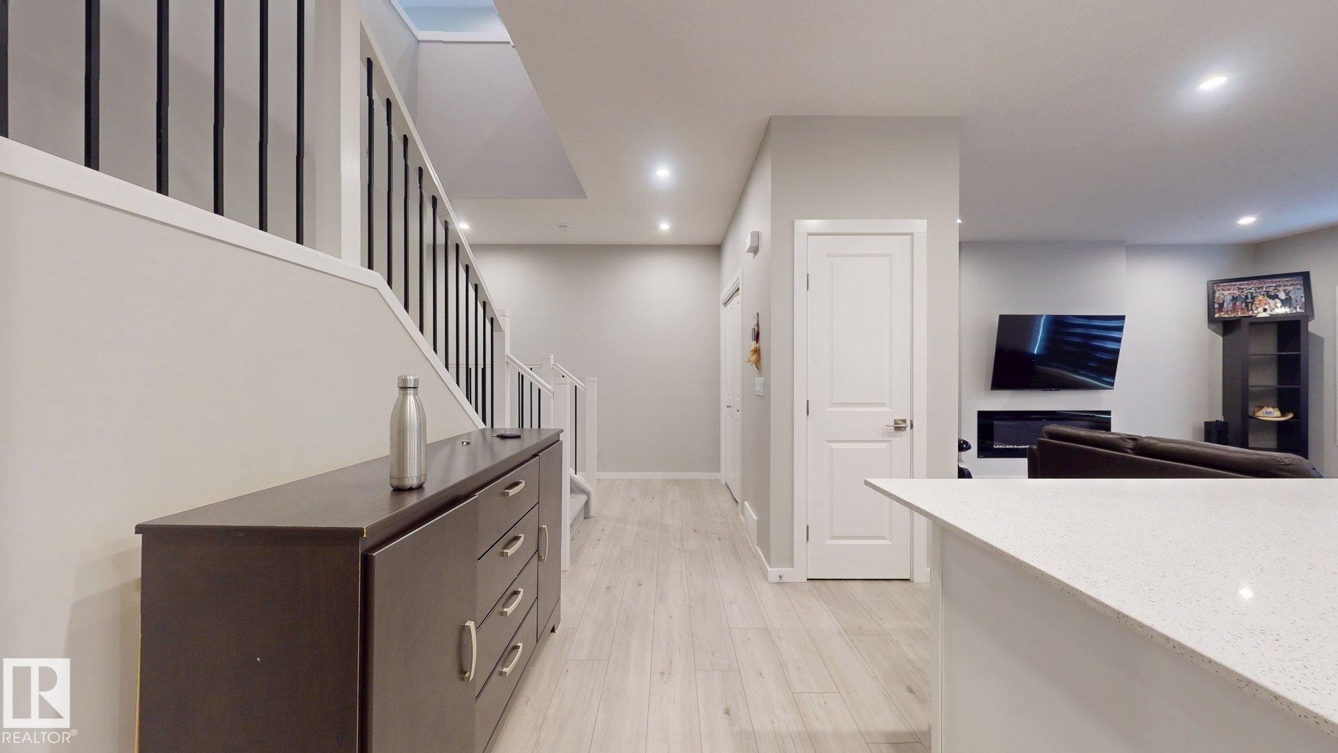 Bright interior with wood-finish flooring, recessed lighting, white trim, and a contemporary staircase featuring black spindles - 607 31 Avenue, Edmonton, AB