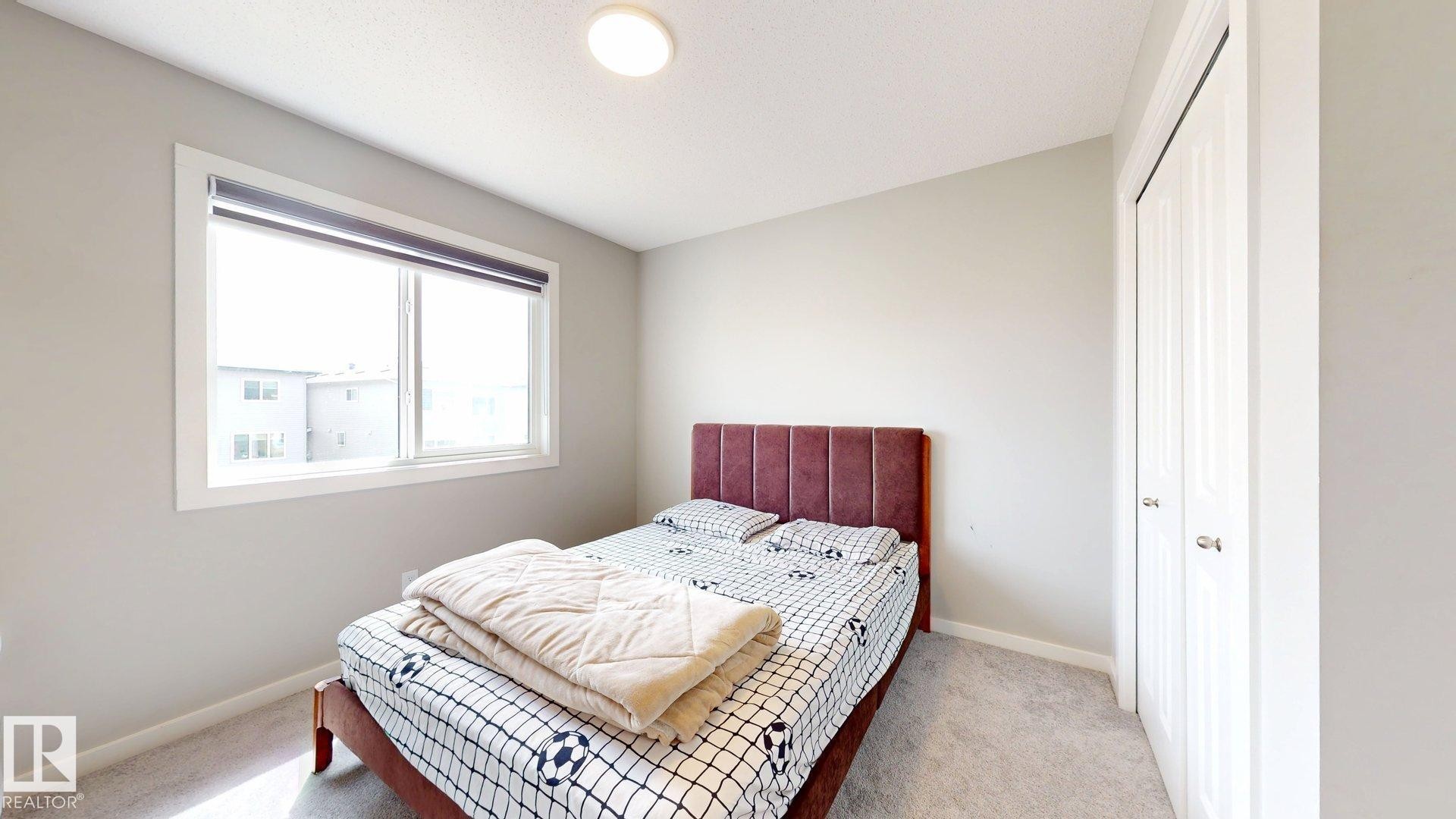 Bedroom featuring a double window, light gray wall paint, and a built-in closet with bifold doors - 607 31 Avenue, Edmonton, AB