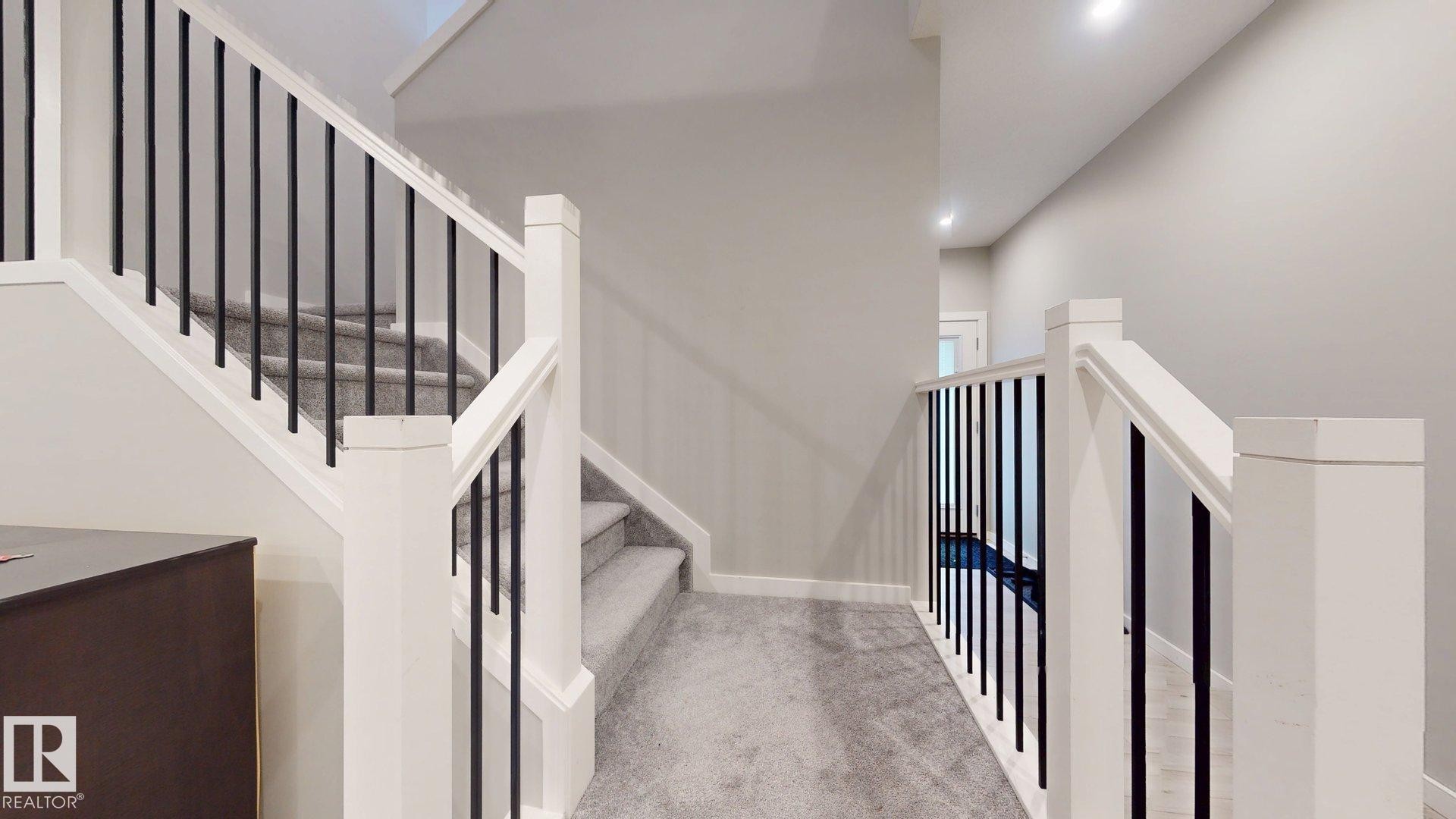 Staircase featuring white newel posts and handrails with contrasting black metal balusters - 607 31 Avenue, Edmonton, AB