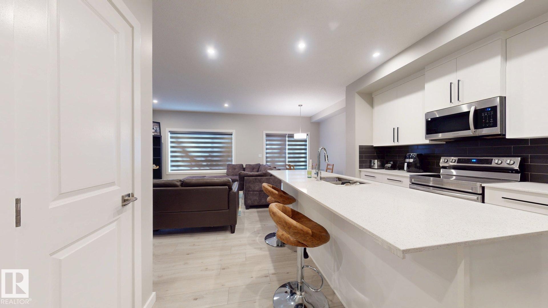 Modern kitchen island with a white countertop and seating for three - 607 31 Avenue, Edmonton, AB