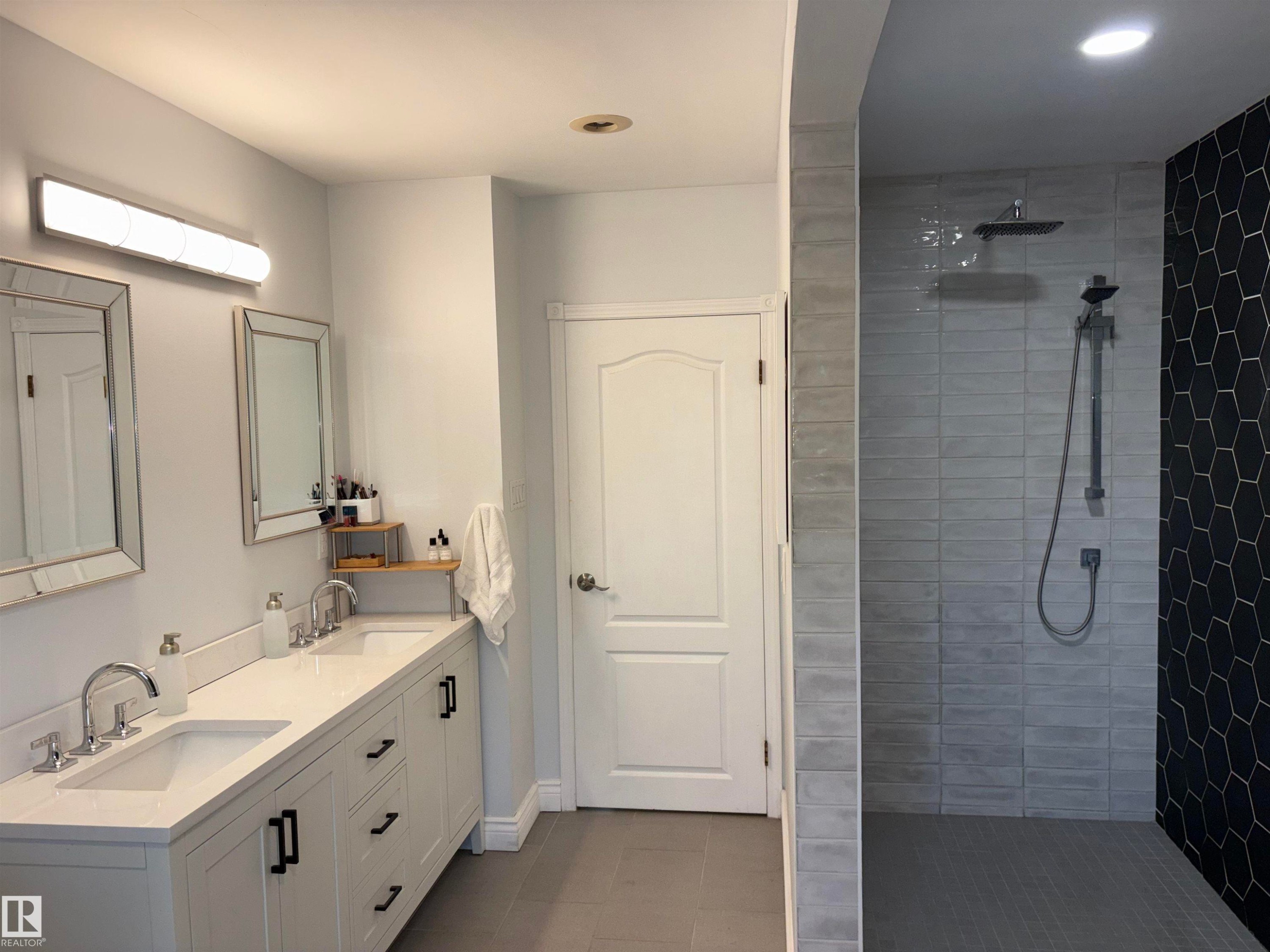 Spacious bathroom featuring a dual vanity with white cabinetry, polished chrome fixtures, and a white countertop - 14016 85 Avenue Nw, Edmonton, AB - Indoor Photo Showing Bathroom